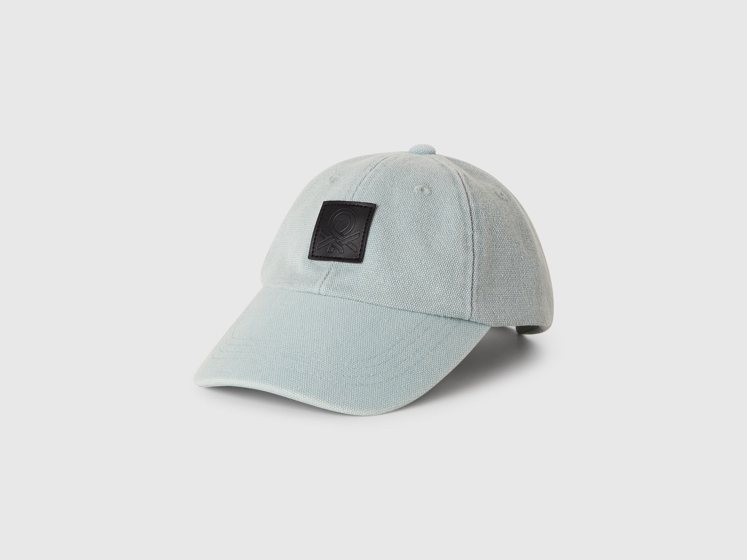 Front view of a male model wearing a classic Benetton branded baseball cap.
