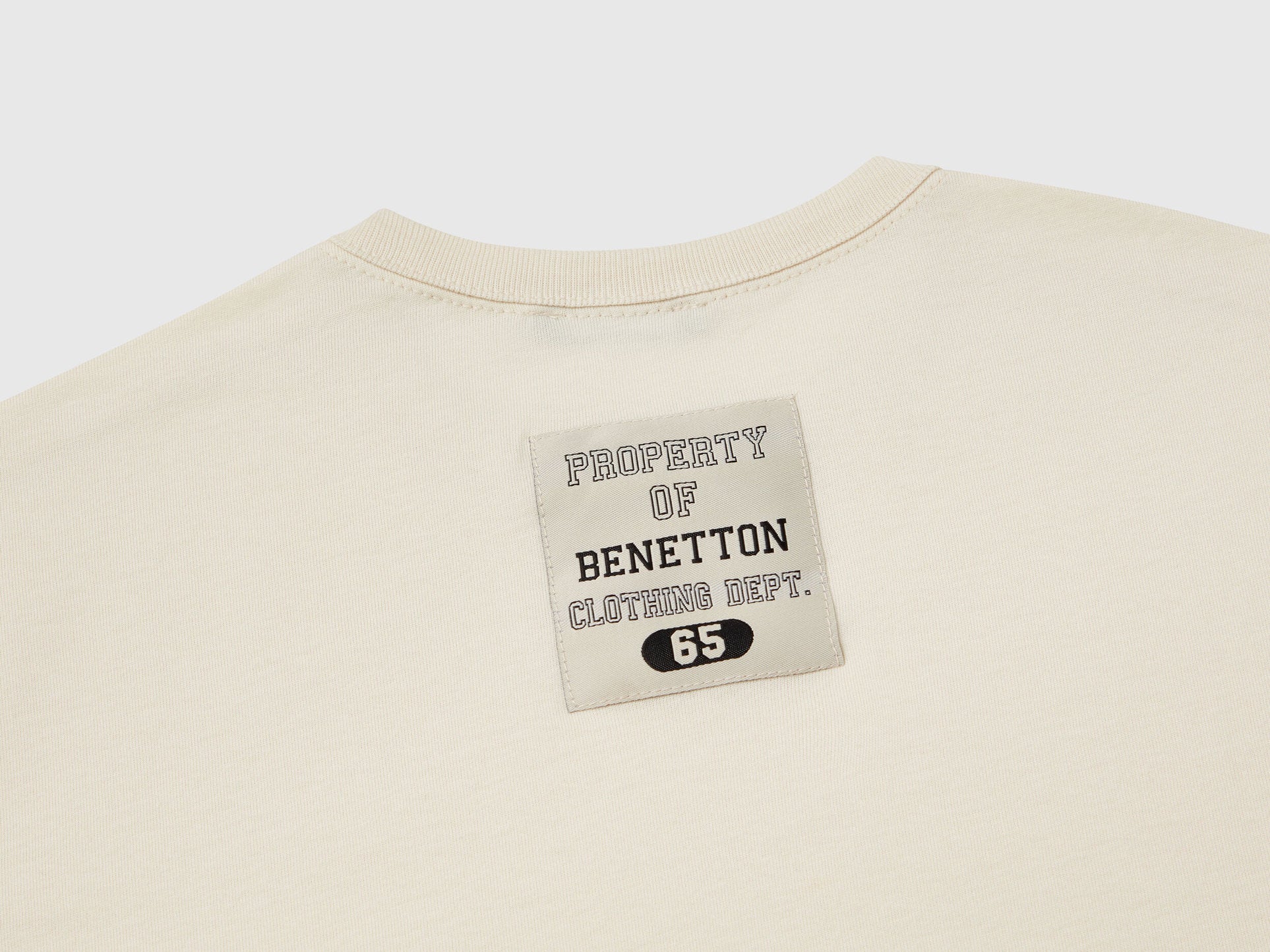 Close-up of the red and white Benetton logo on a dark blue checkered jacket.