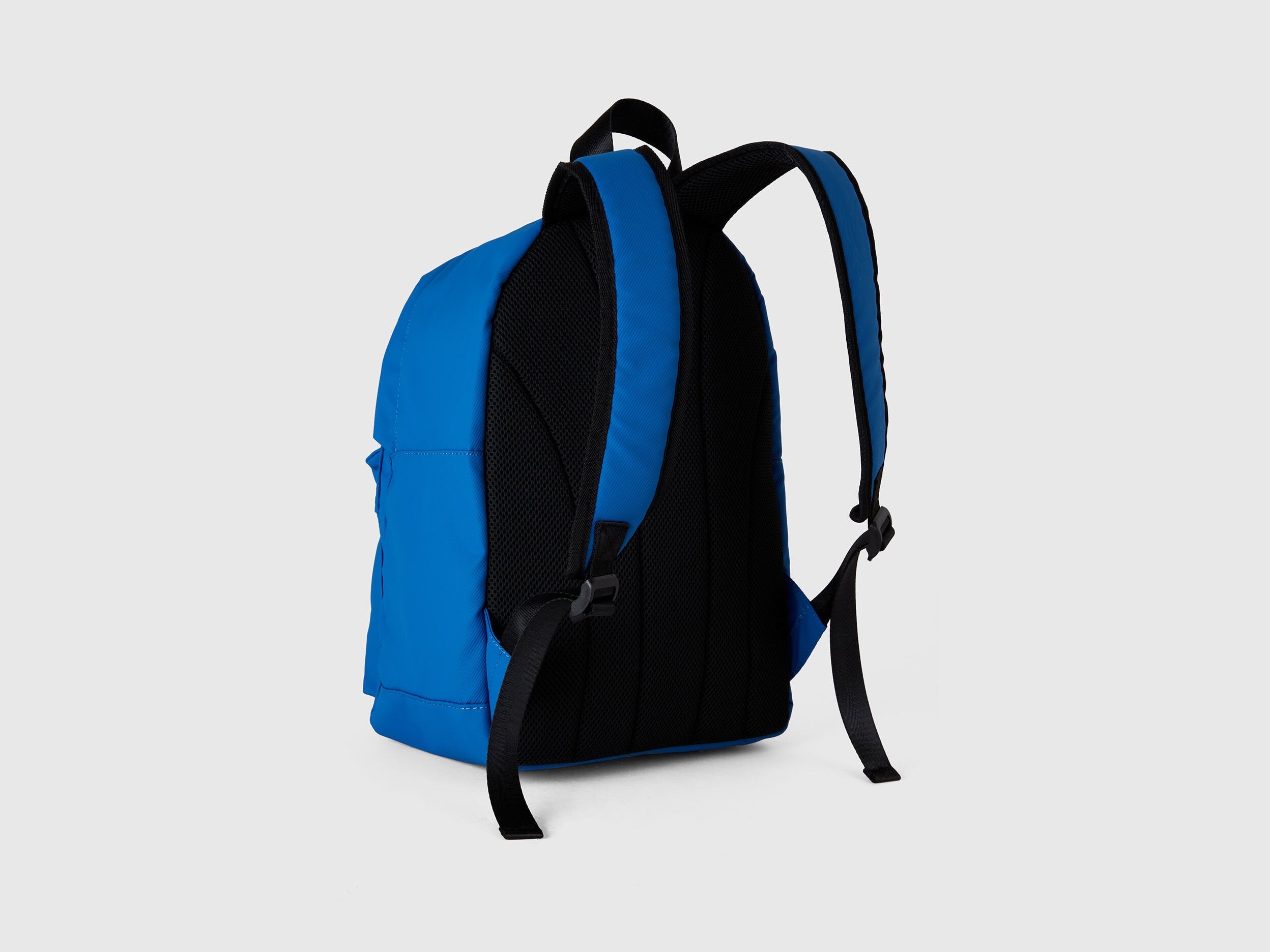 Side view of a blue and black nylon backpack, showcasing the padded shoulder straps and back panel.