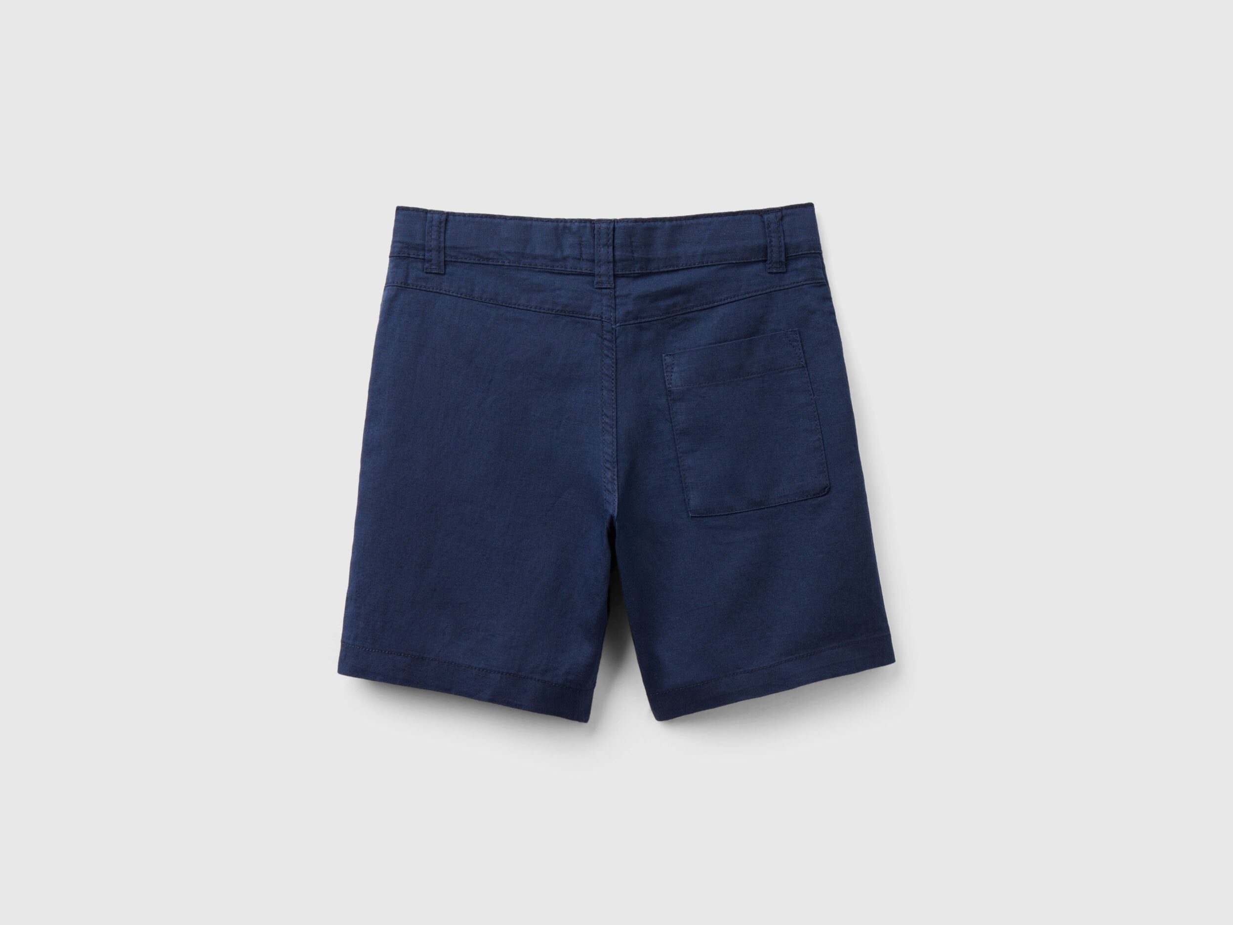 A full, flat lay shot of a pair of dark blue linen blend shorts, viewed from the back.