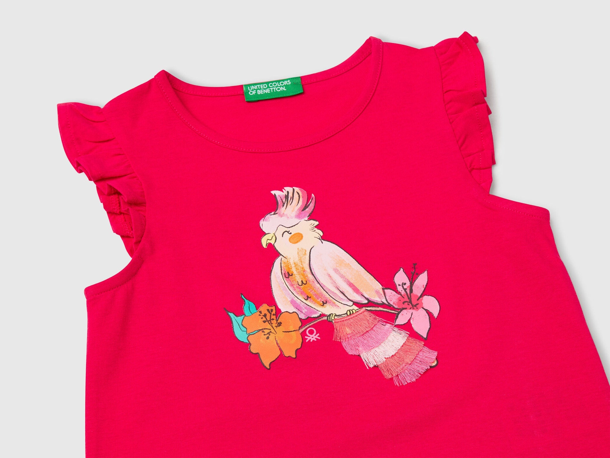 Close-up of the vibrant bird print on a fuchsia Benetton tank top, showing feather details.