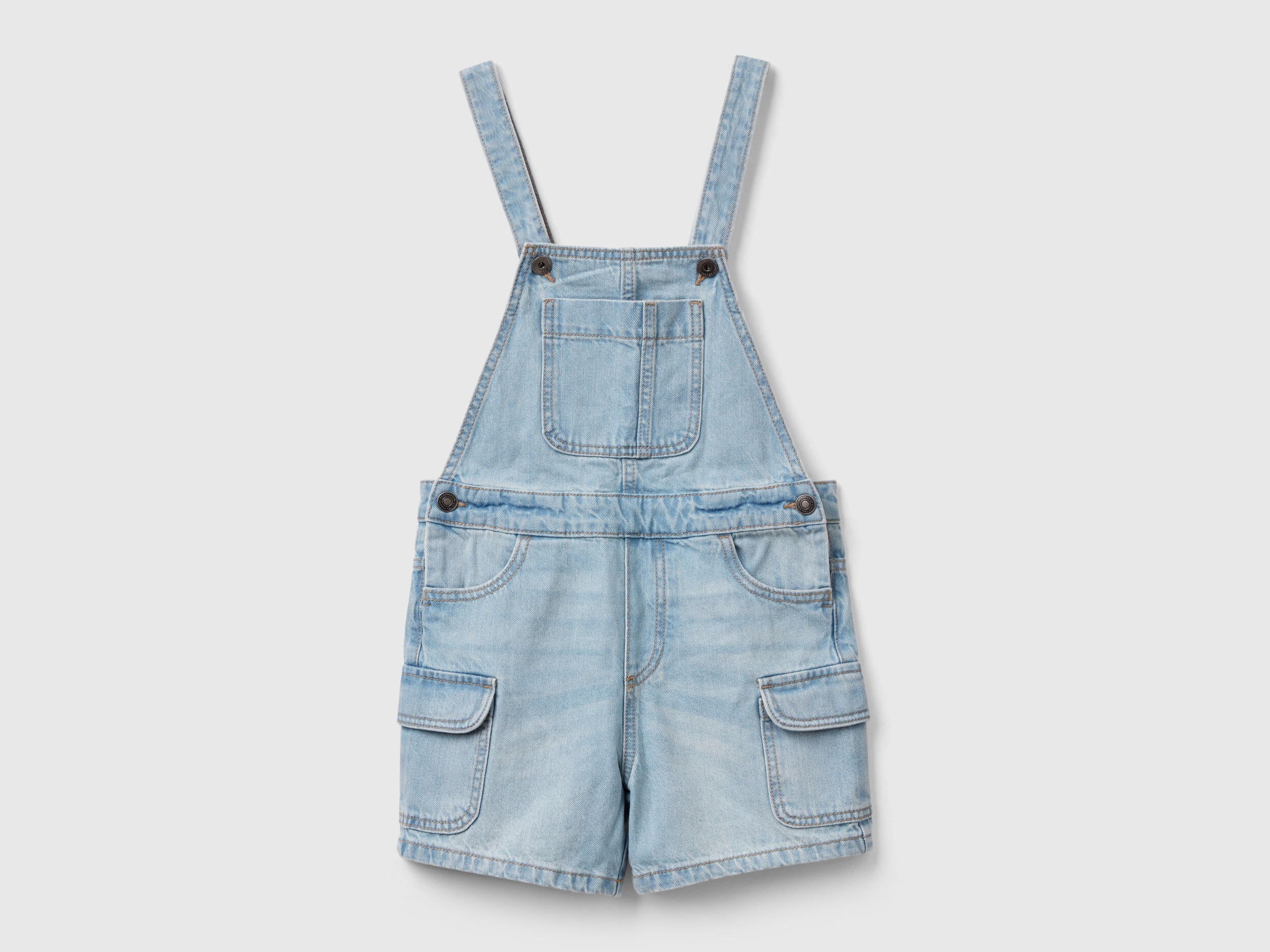 Front view of light wash denim dungaree shorts for girls in Kuwait with front pockets.