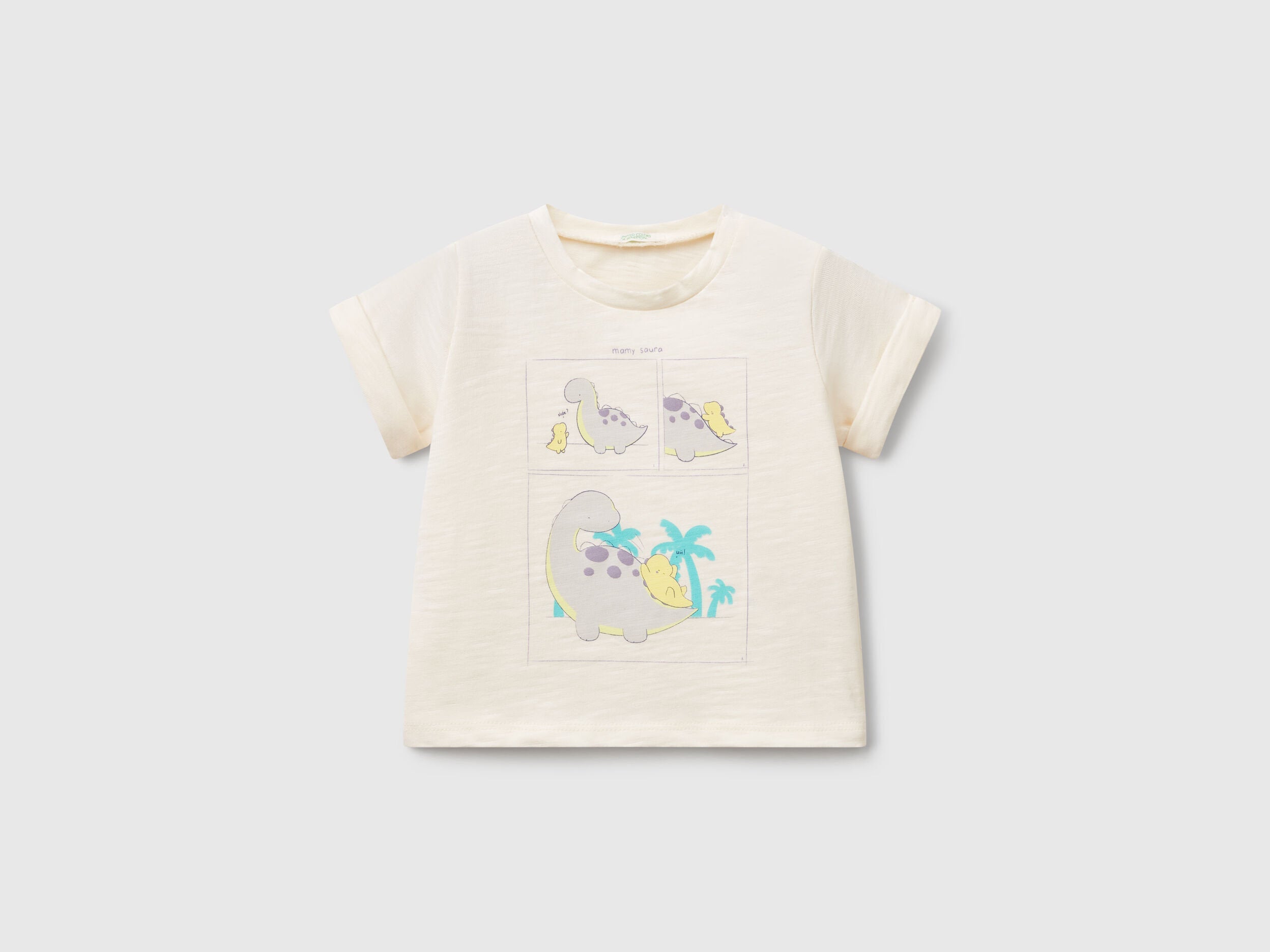 Front view of an off-white T-shirt for kids in Kuwait, featuring adorable graphic prints of cartoon dinosaurs and a palm tree, perfect for casual wear.