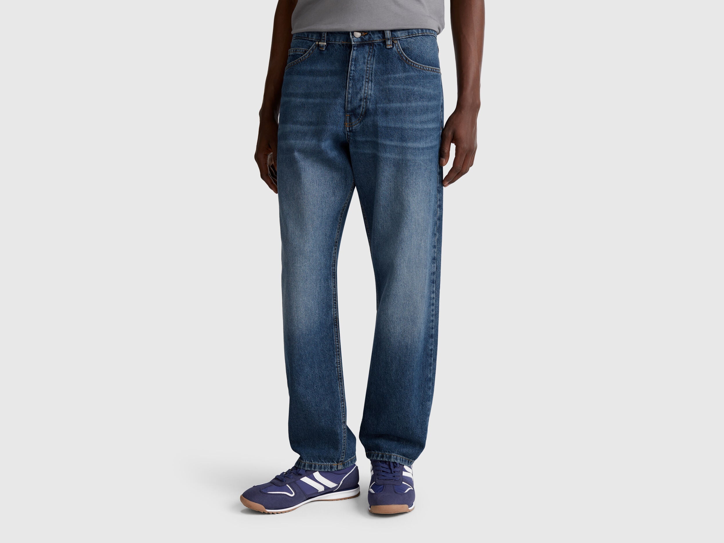 Full-length back view of a man wearing blue slim-fit jeans.