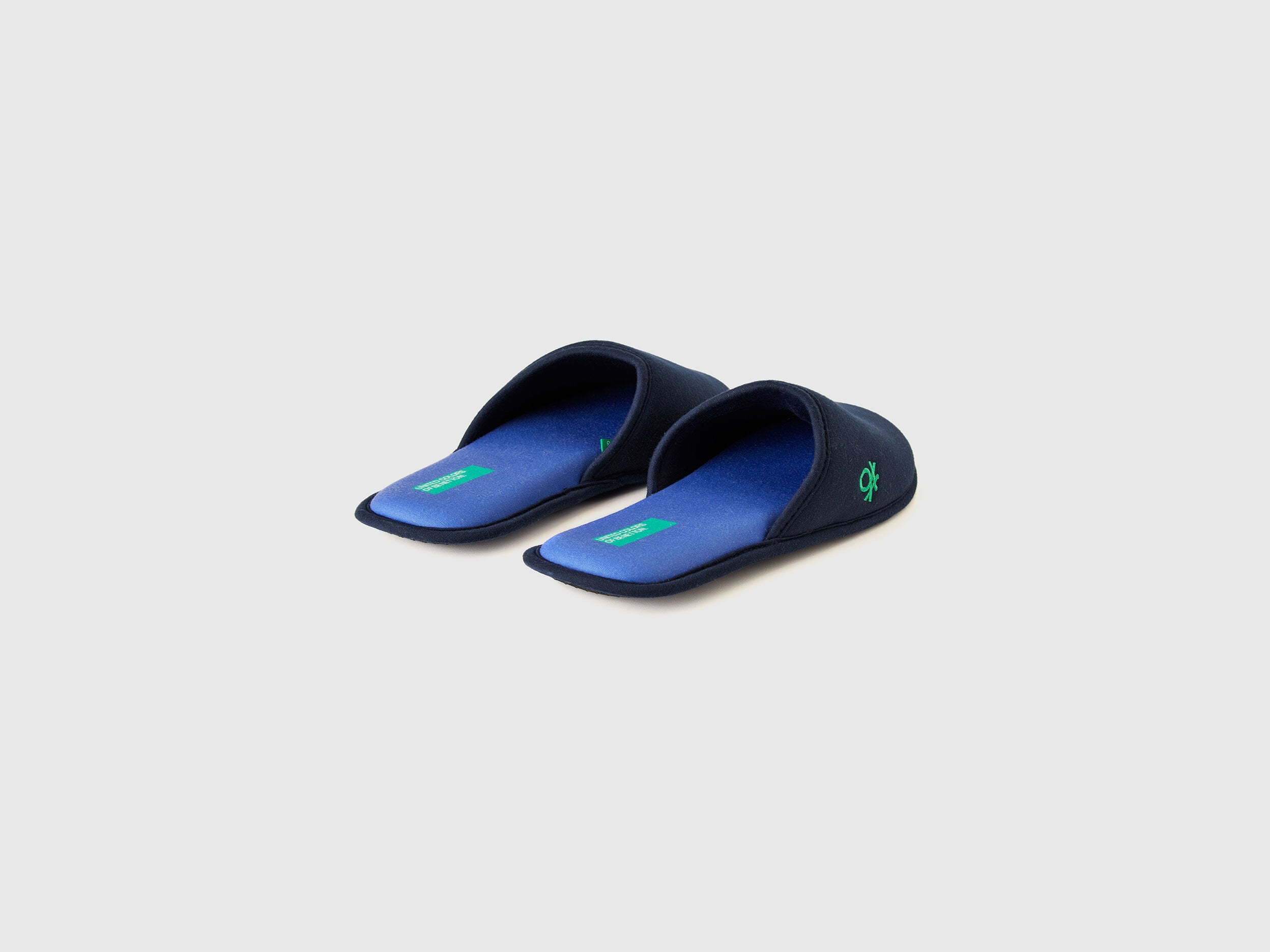 Pair of navy blue slippers with blue insoles and a green logo.