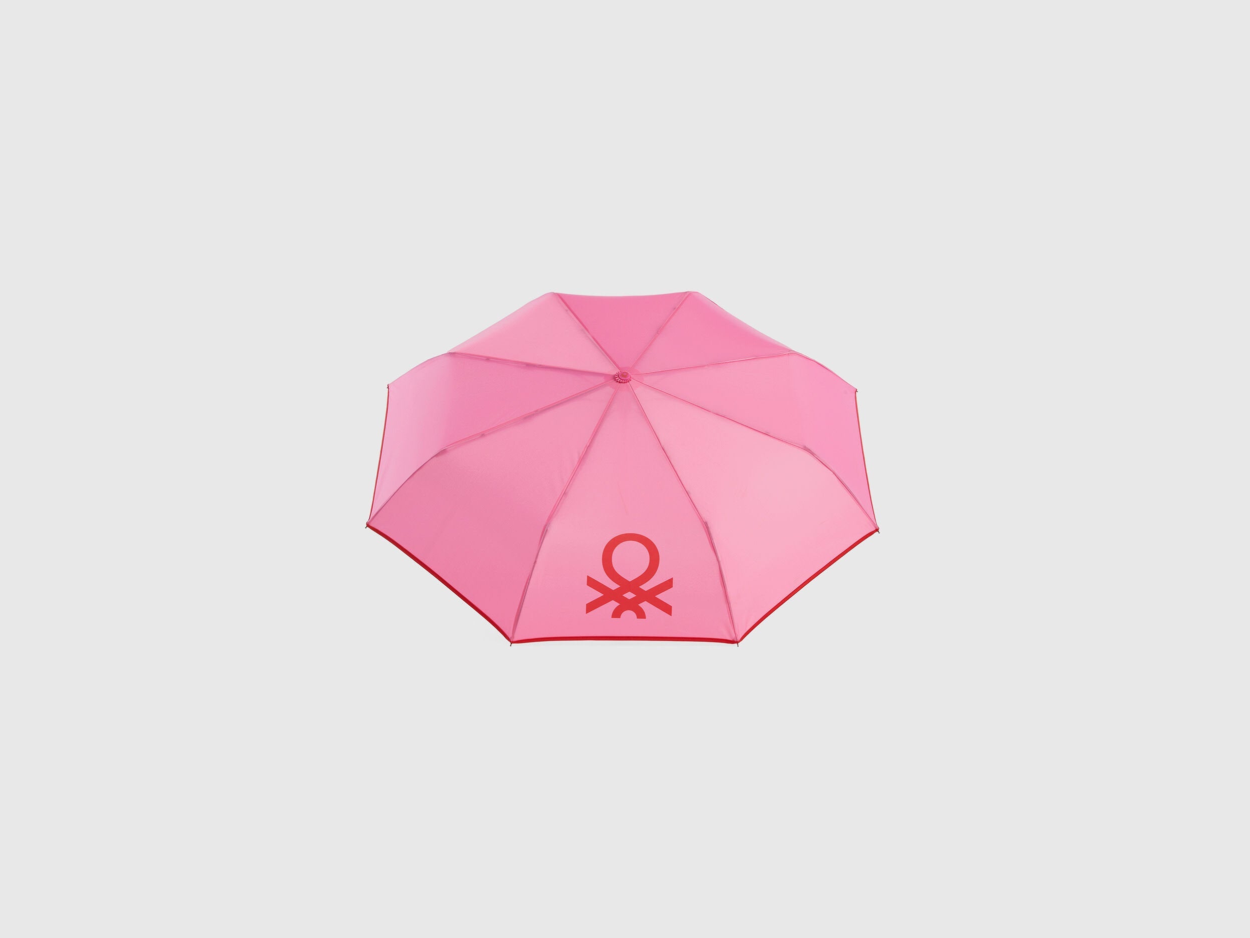 Open pink Benetton umbrella, top view for rain protection.