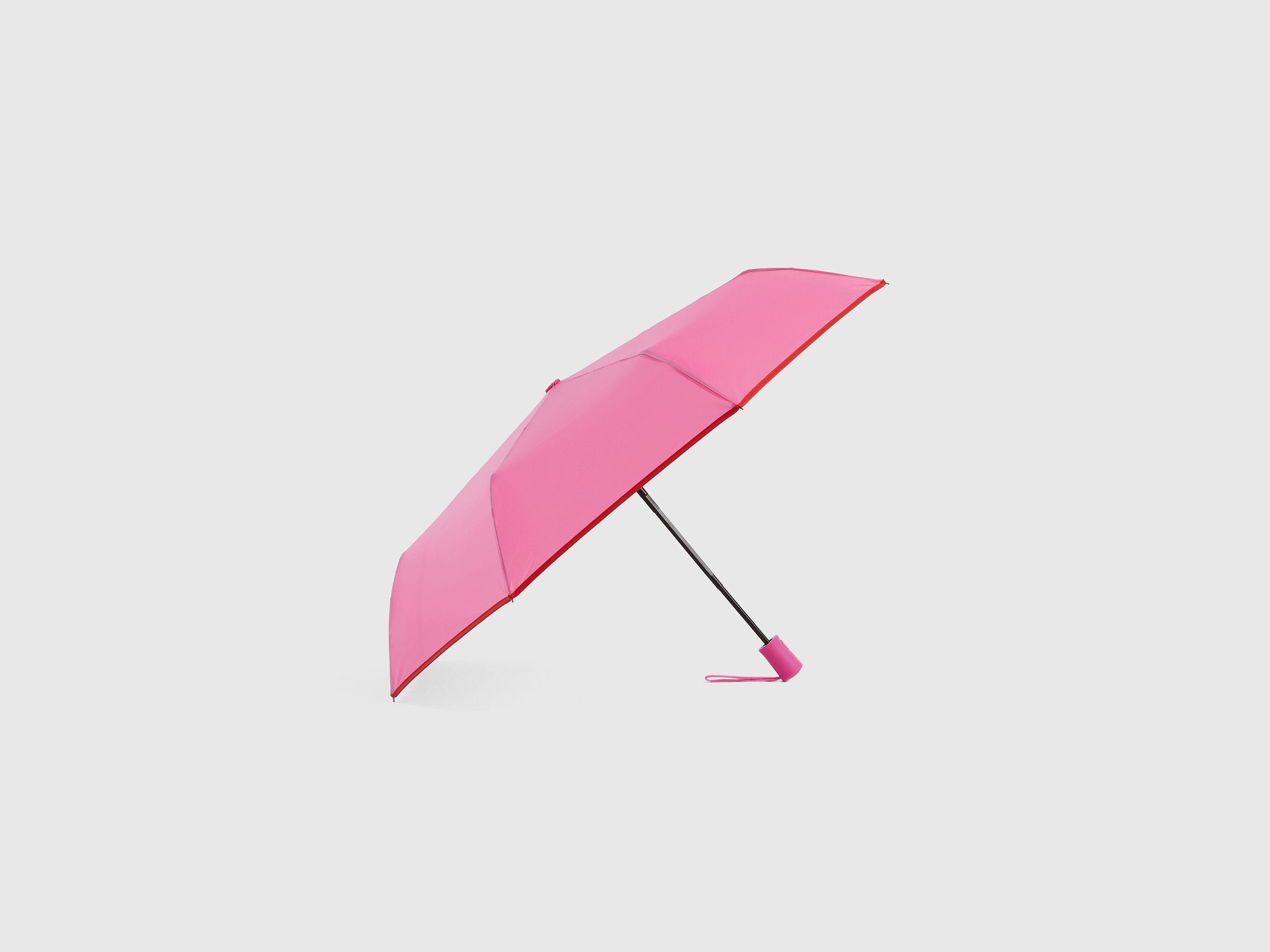 Pink Benetton umbrella, partially open, stylish rain gear.
