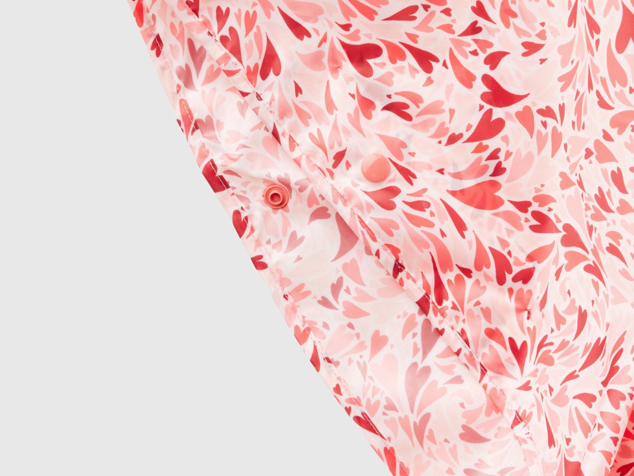 Close-up of a pink and white patterned rain poncho, showing abstract floral or leaf design.