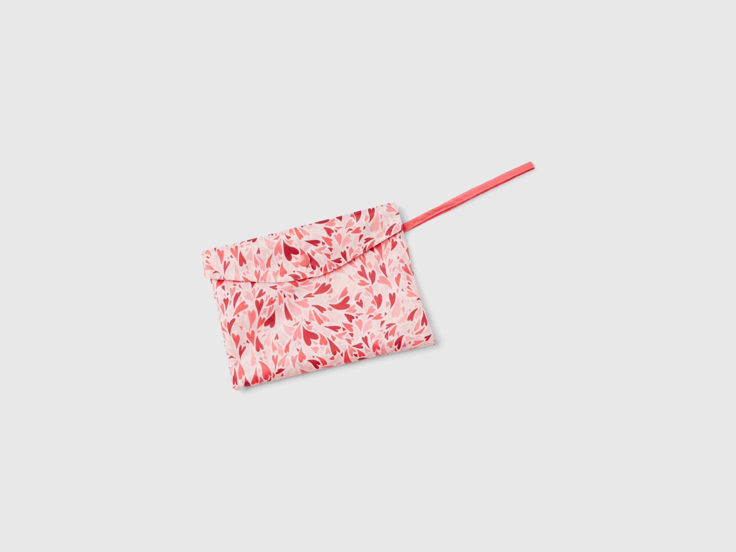 Folded pink and white patterned rain poncho, compact in its matching pouch. Portable.