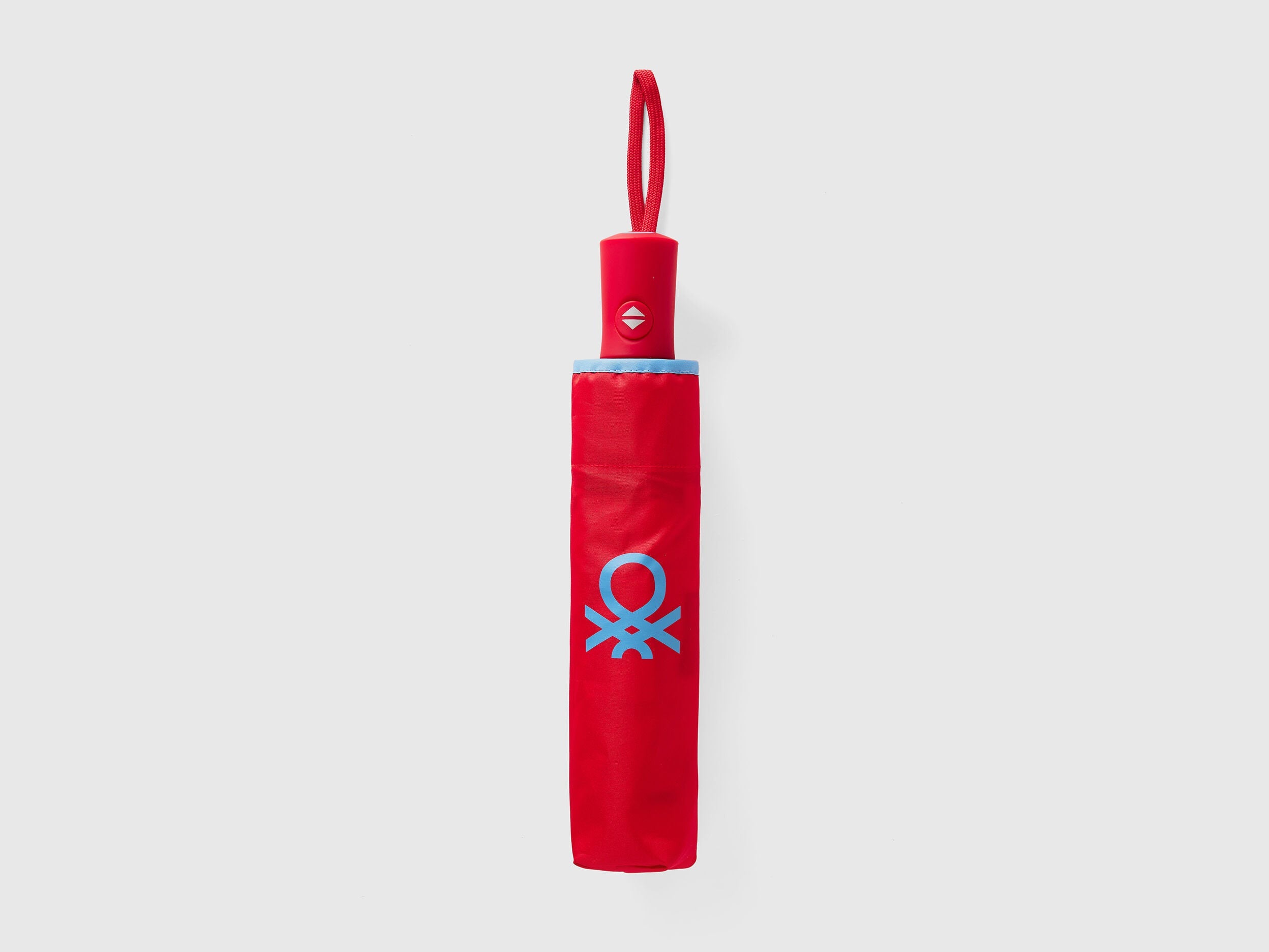 Folded red Benetton umbrella, compact for portability.