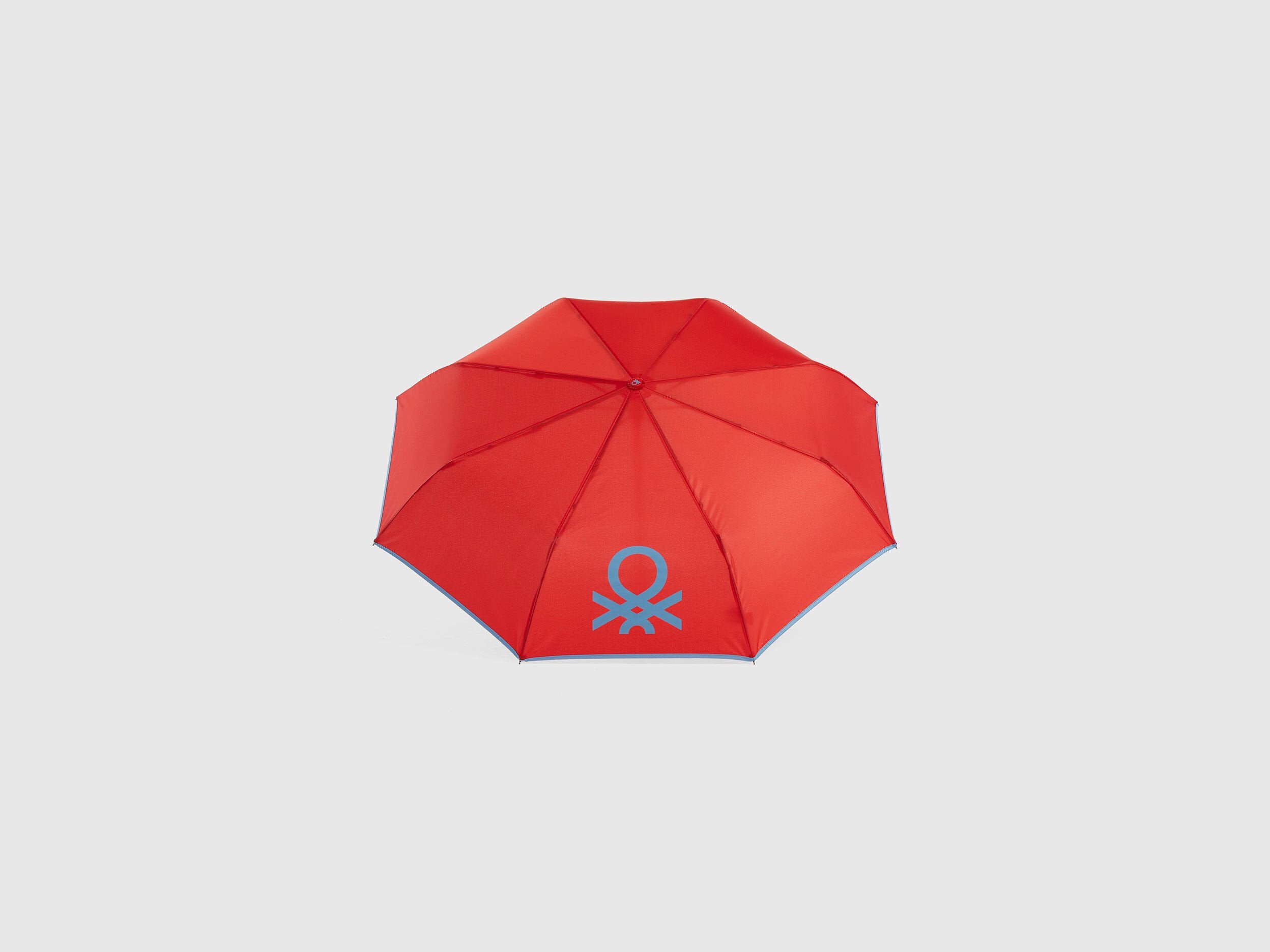 Open red Benetton umbrella, top view for rain protection.