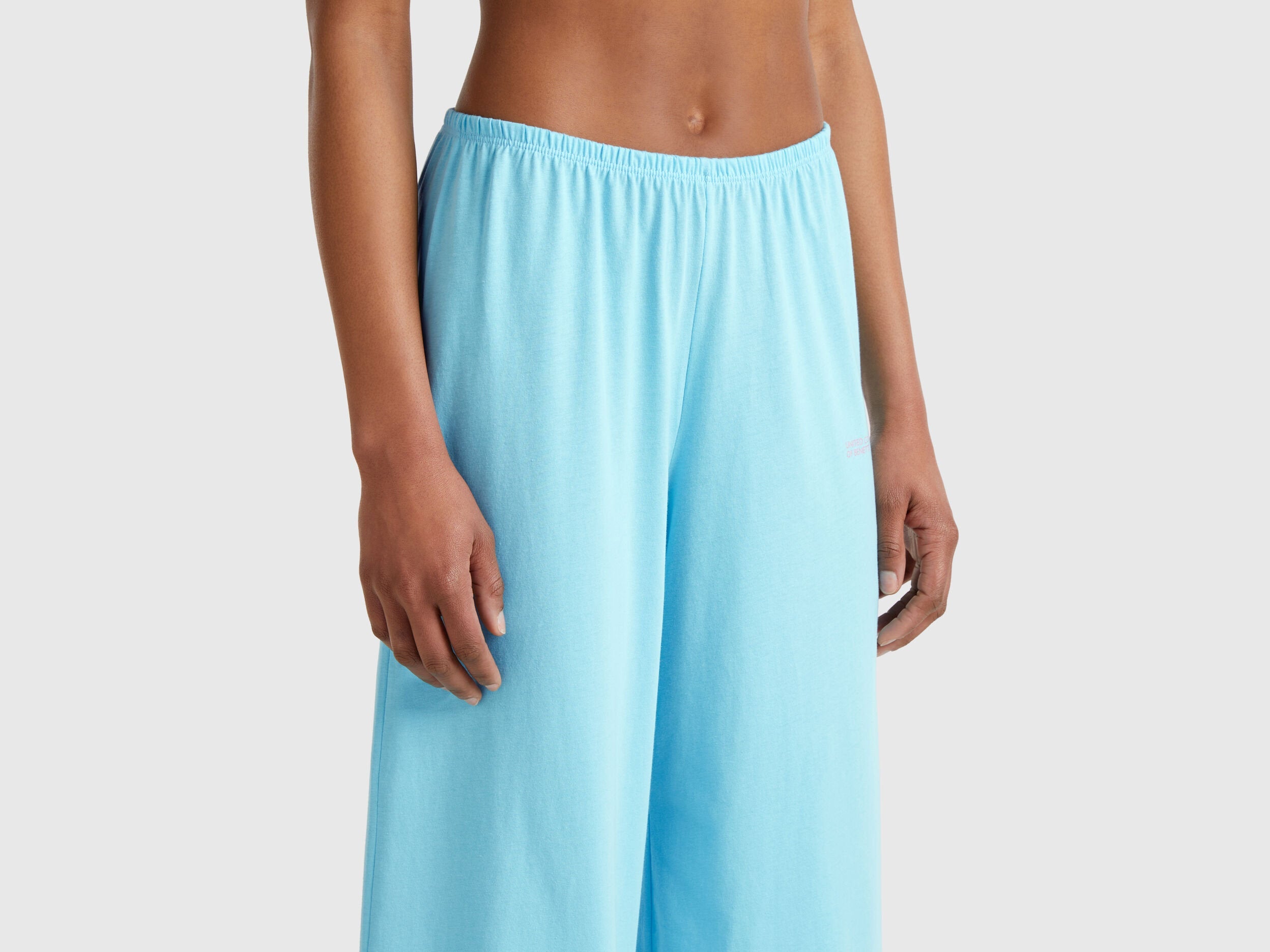 Close-up of the bottom half of a light blue loose-fitting pyjama set for women.