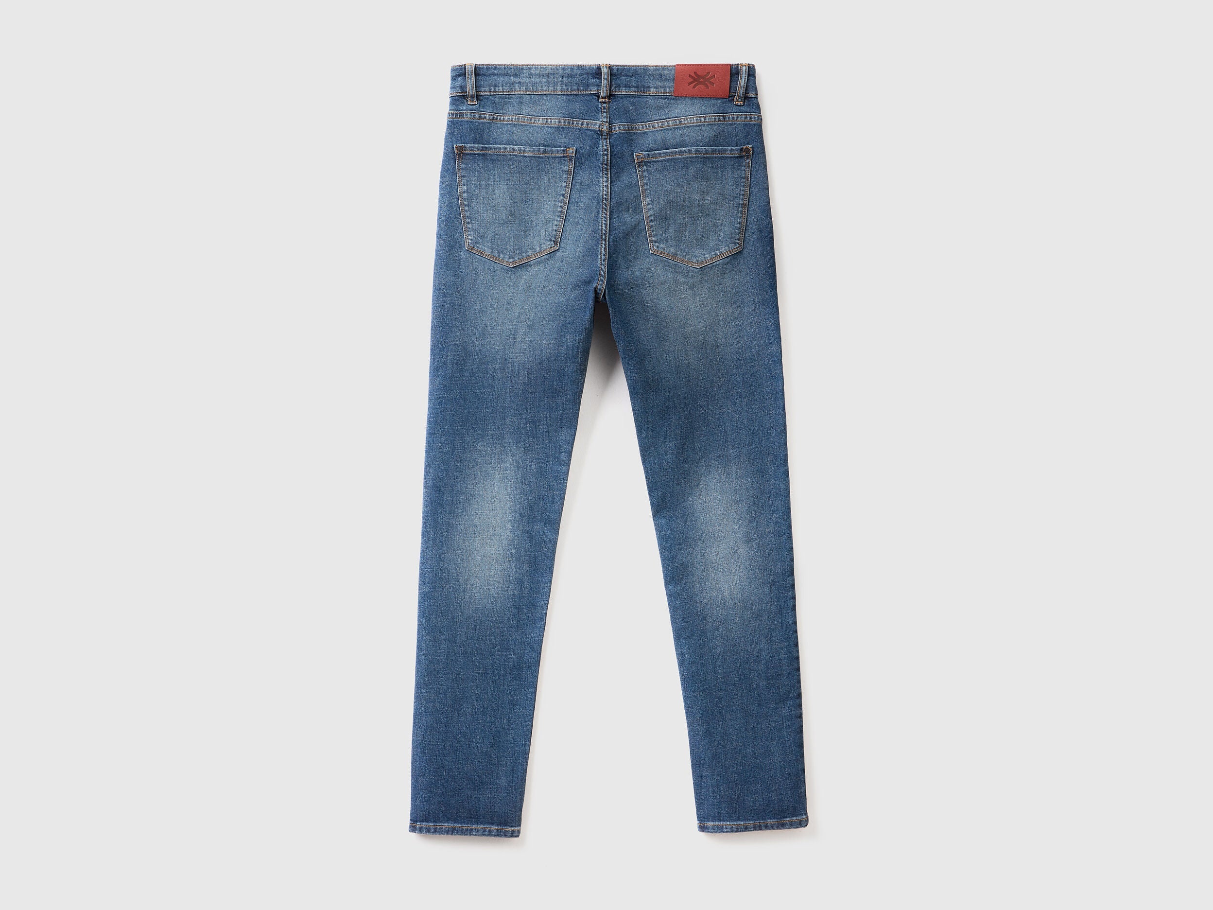 Back view of blue skinny jeans for men, flat lay. Features classic pockets and belt loops.