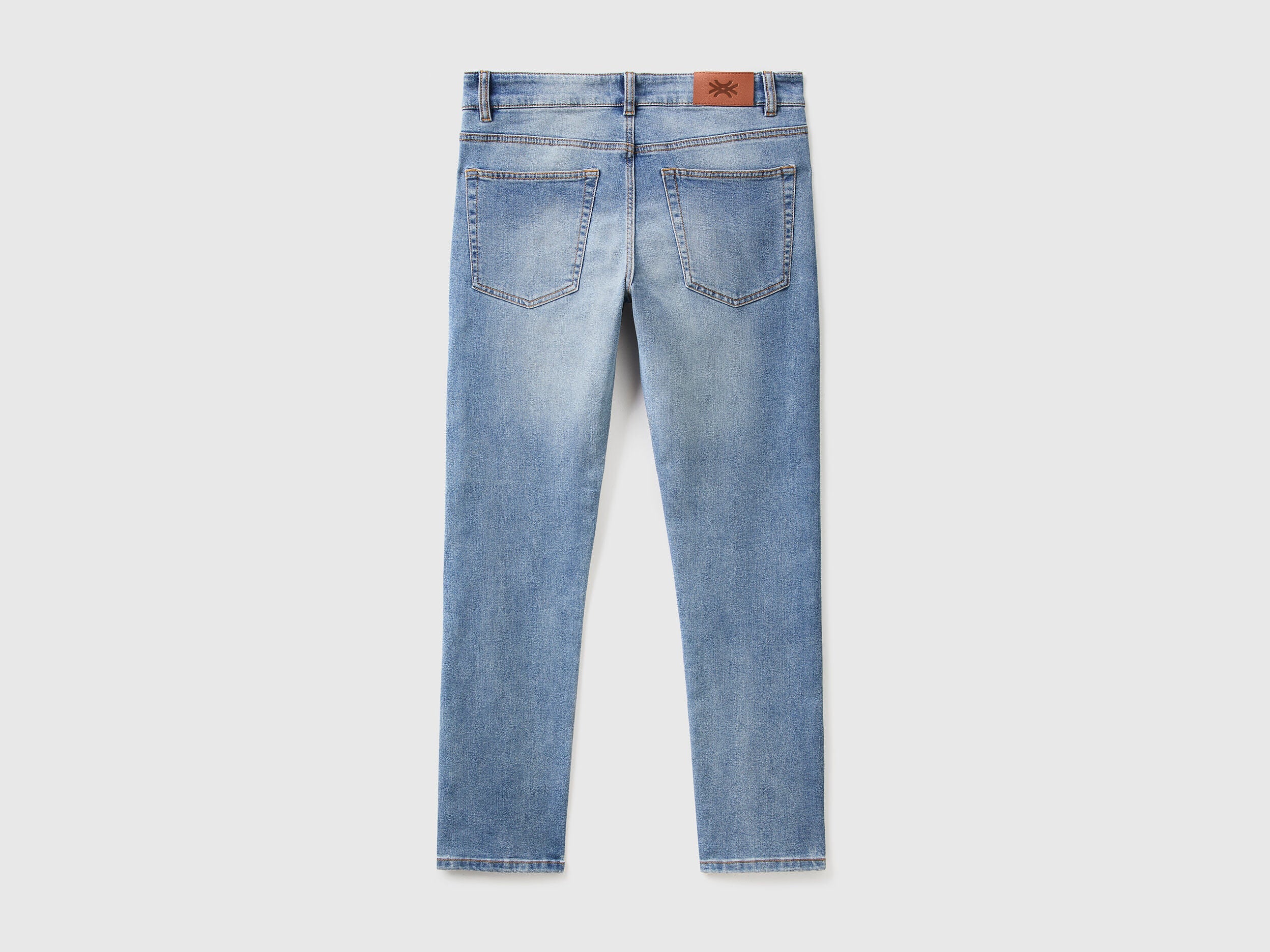 Close-up of the back pocket and stitching on black slim-fit jeans.