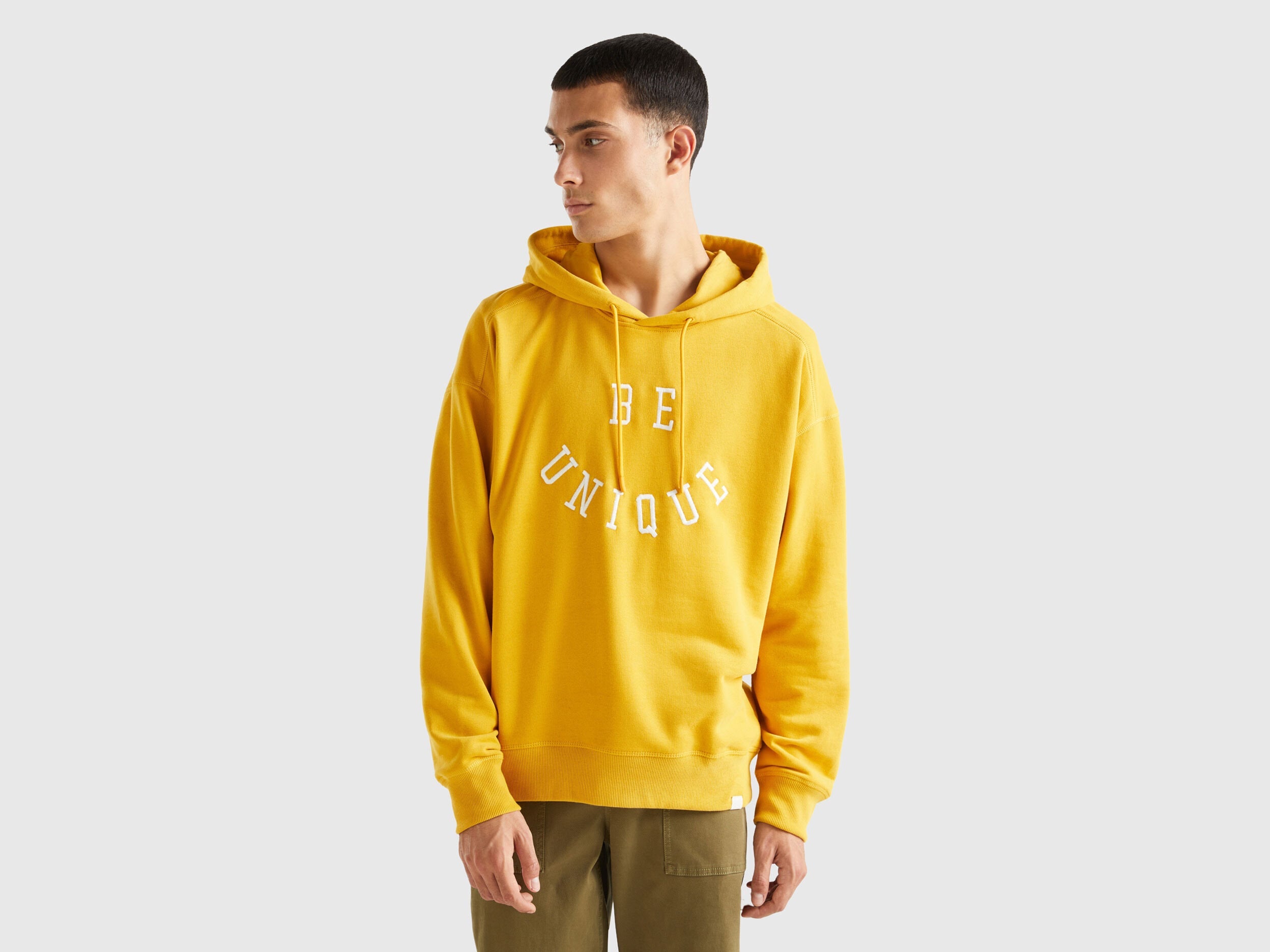 Front view of a man wearing a yellow hoodie with graphic print.