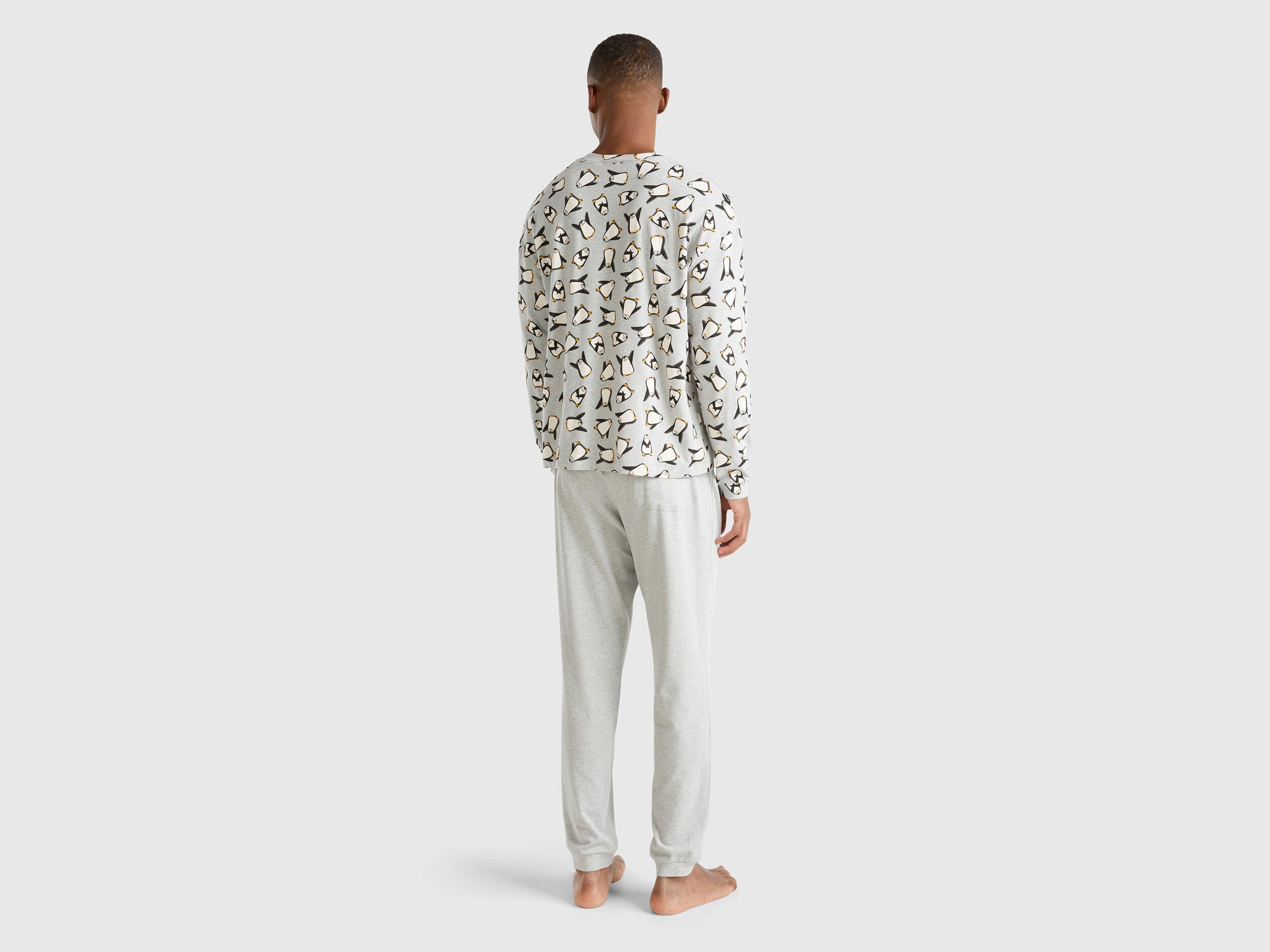 Full-length back view of a man wearing white pyjamas with a penguin print in Kuwait.