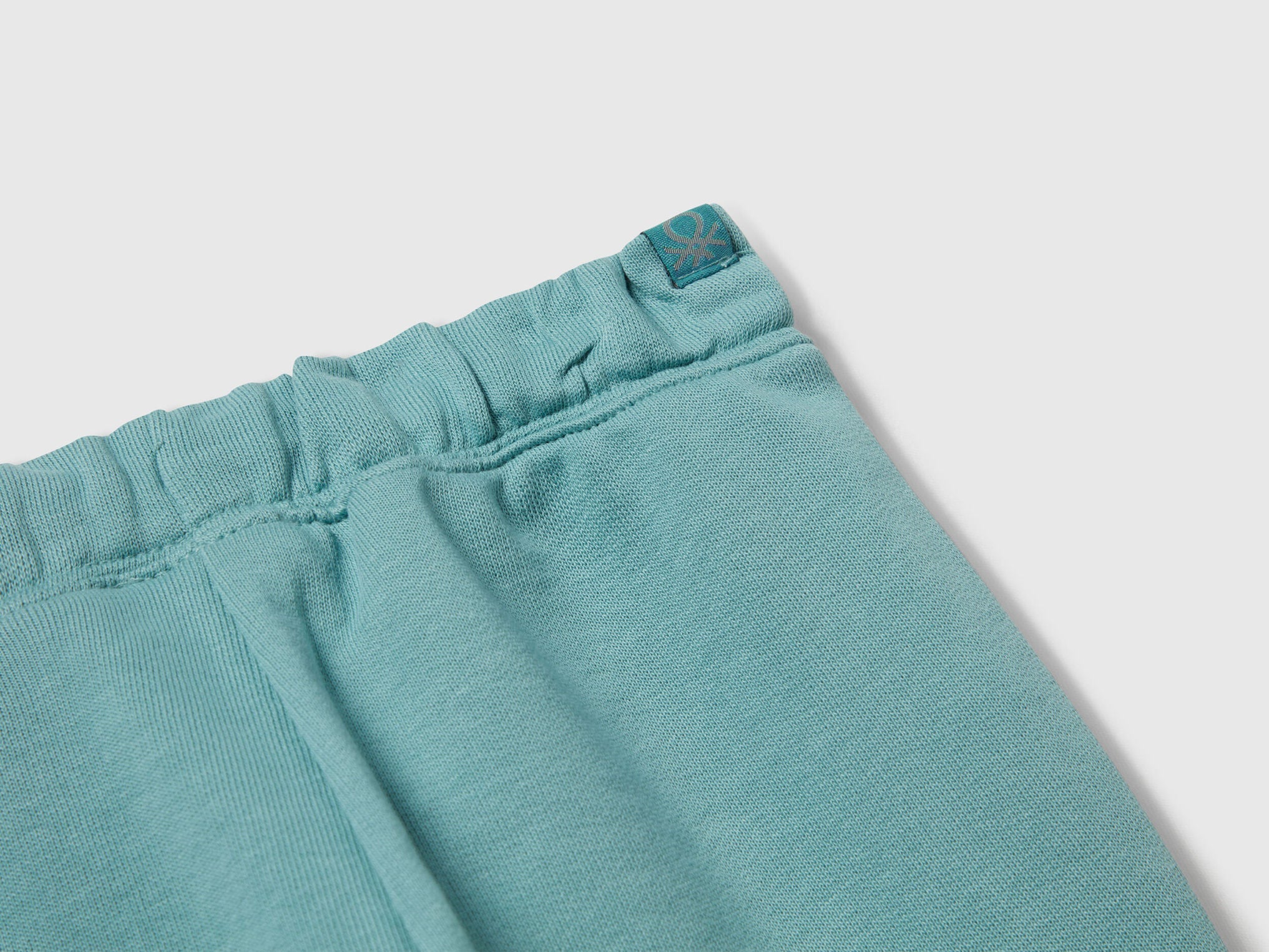 Benetton blue cotton joggers side view showing elastic waist detail.