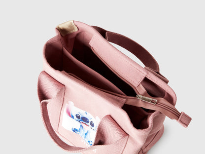 Top-down view of the open interior of a pink Benetton x Lilo &amp; Stitch Disney bag, revealing spacious compartments and Stitch graphic on the side.