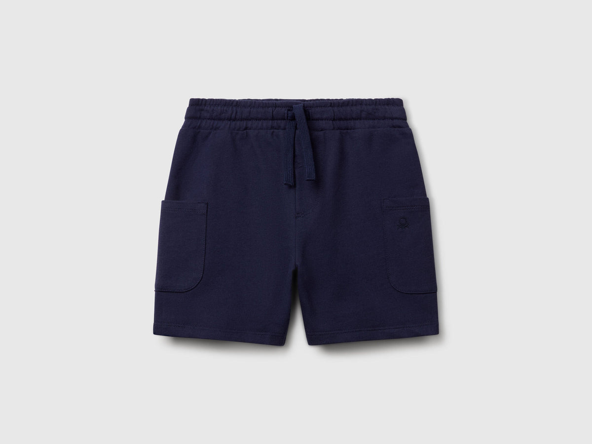 Angled view of navy blue Benetton cotton cargo shorts, showcasing the drawstring waist and practical side pockets.