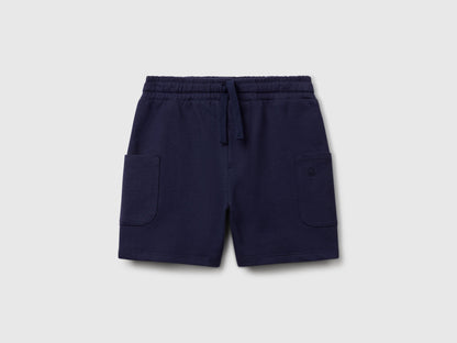 Angled view of navy blue Benetton cotton cargo shorts, showcasing the drawstring waist and practical side pockets.