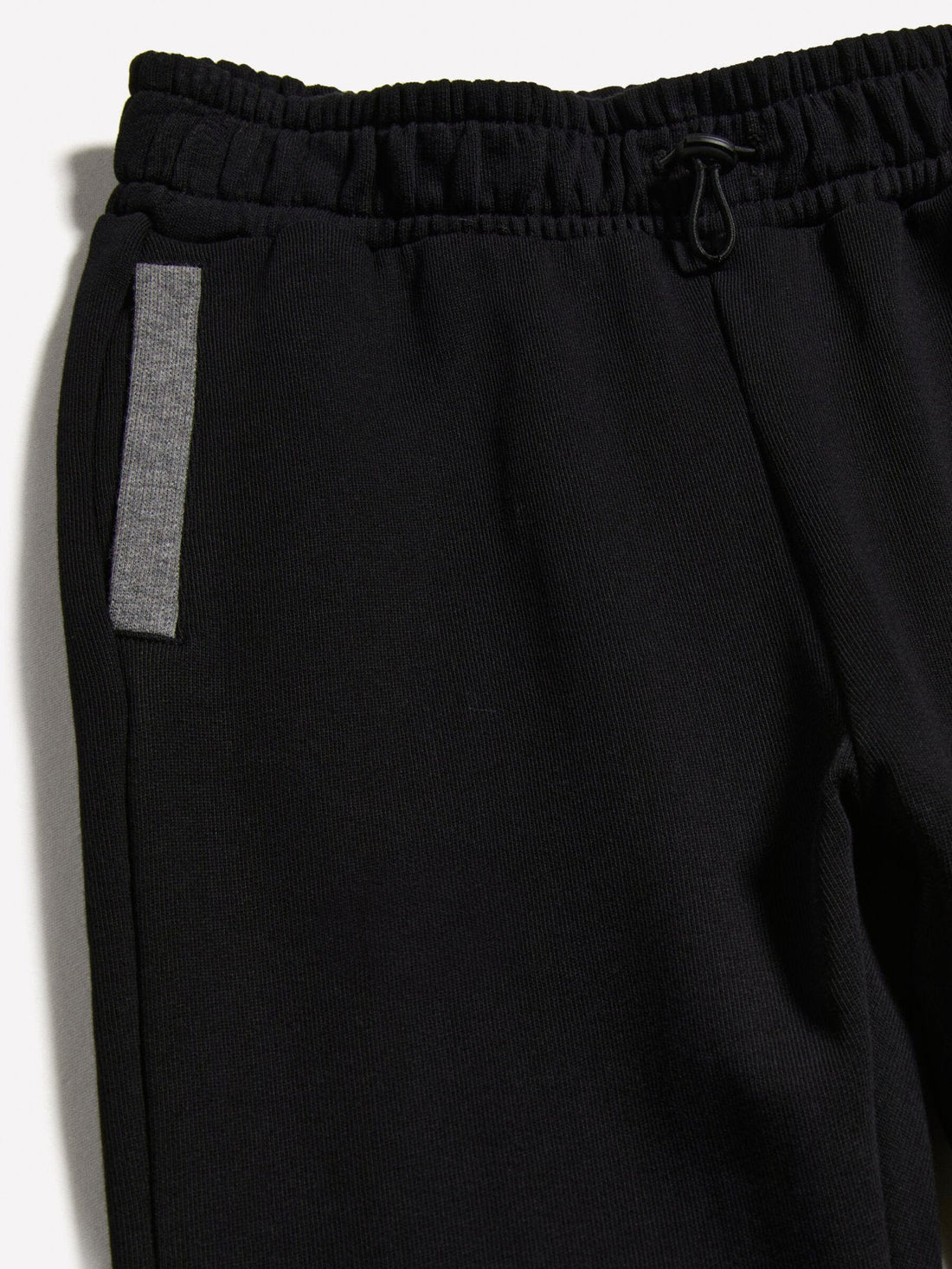 Close-up detail of the black clashing jogger sweatpants, showing the texture of the fabric and the reflective side stripe.