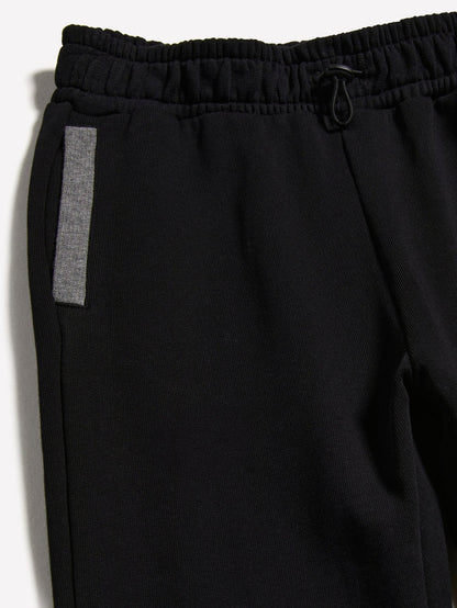Close-up detail of the black clashing jogger sweatpants, showing the texture of the fabric and the reflective side stripe.