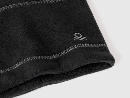 Close-up of black fleece neck warmer with Benetton logo.