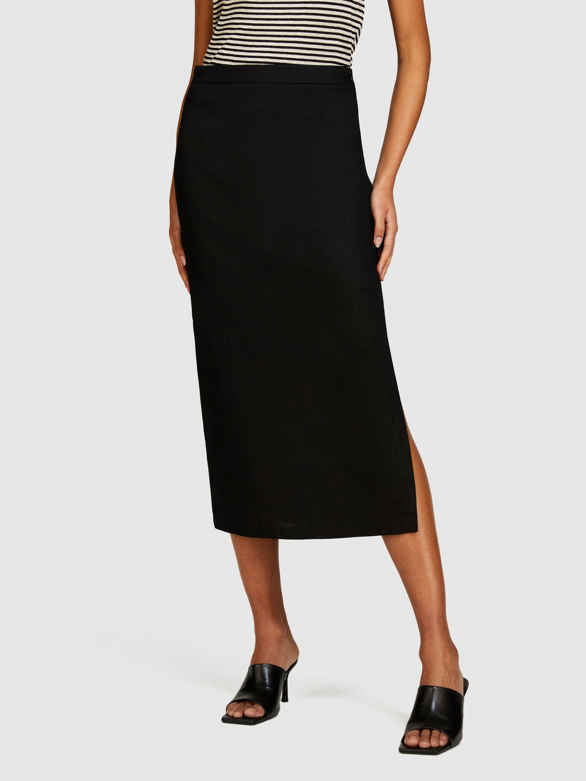 Front view of black pencil skirt with a high slit paired with a striped top.