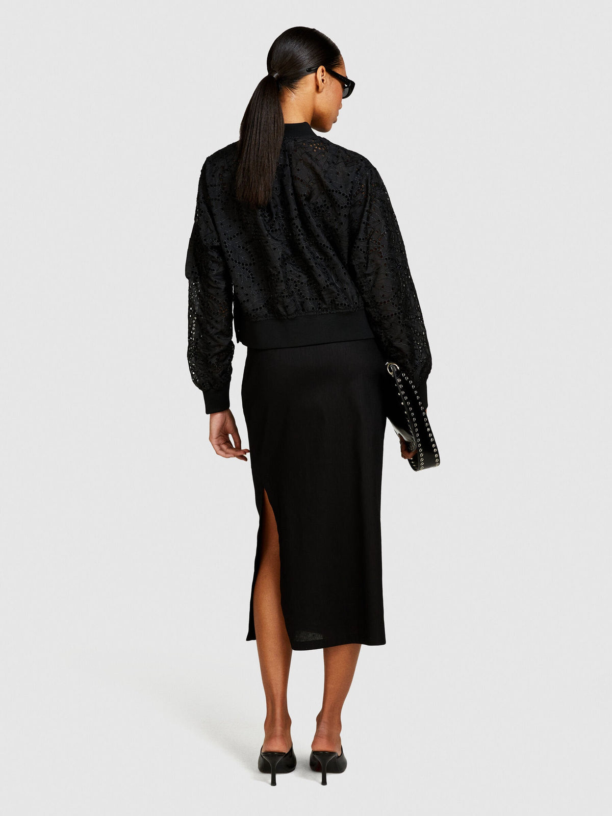 Back view of model wearing a black pencil skirt with a back slit.
