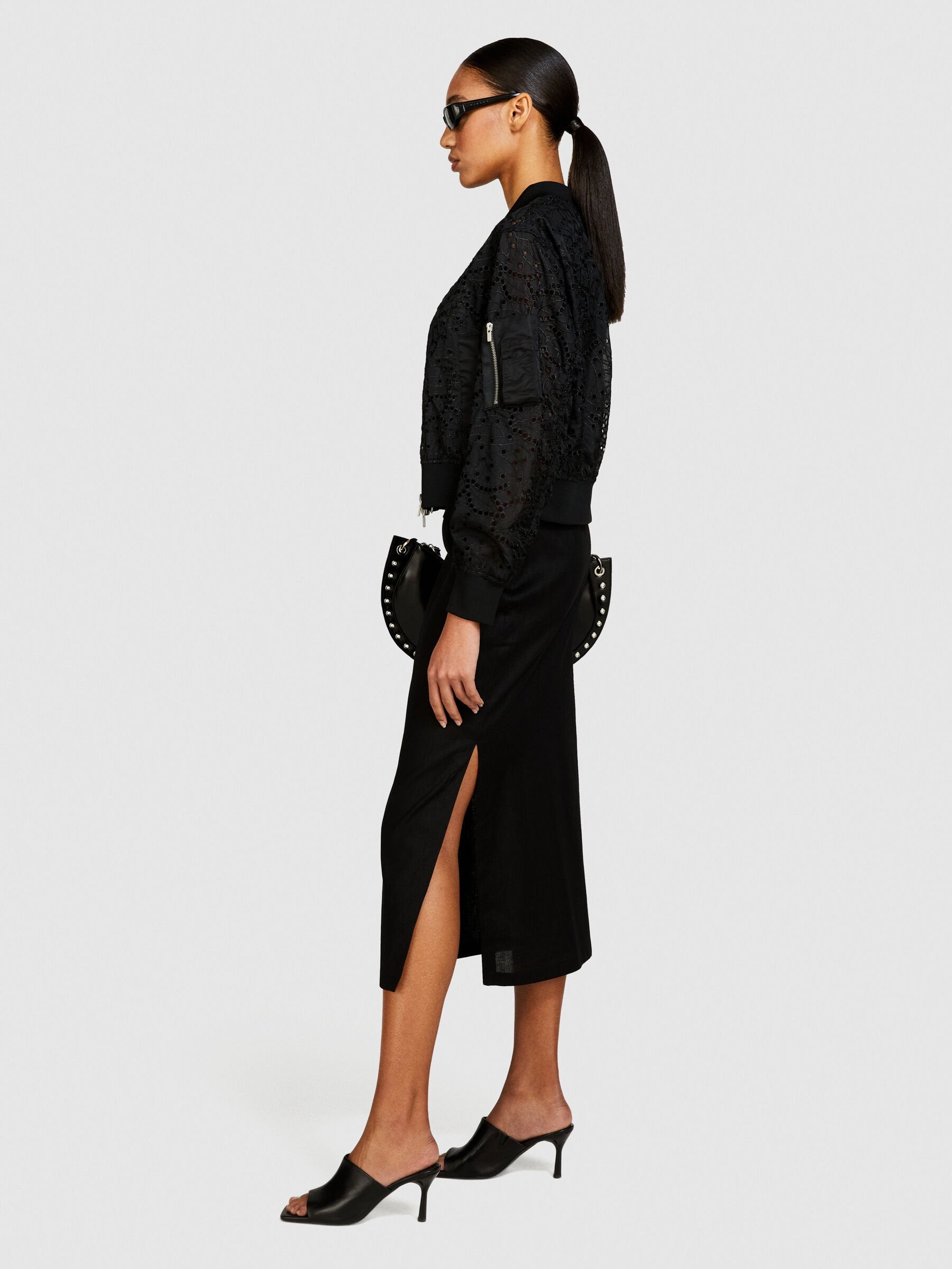 Side view of model wearing a black pencil skirt with a high side slit.