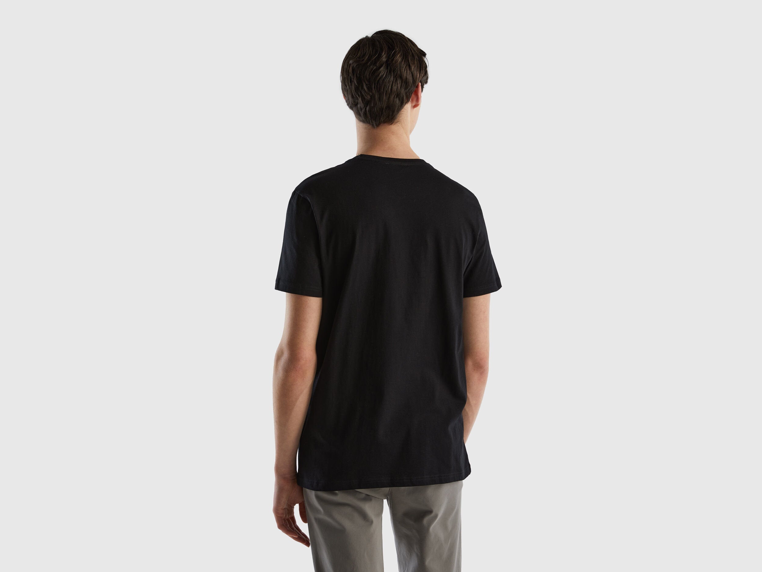 Male model wearing a black t-shirt, shown from the back, highlighting the fit and design.