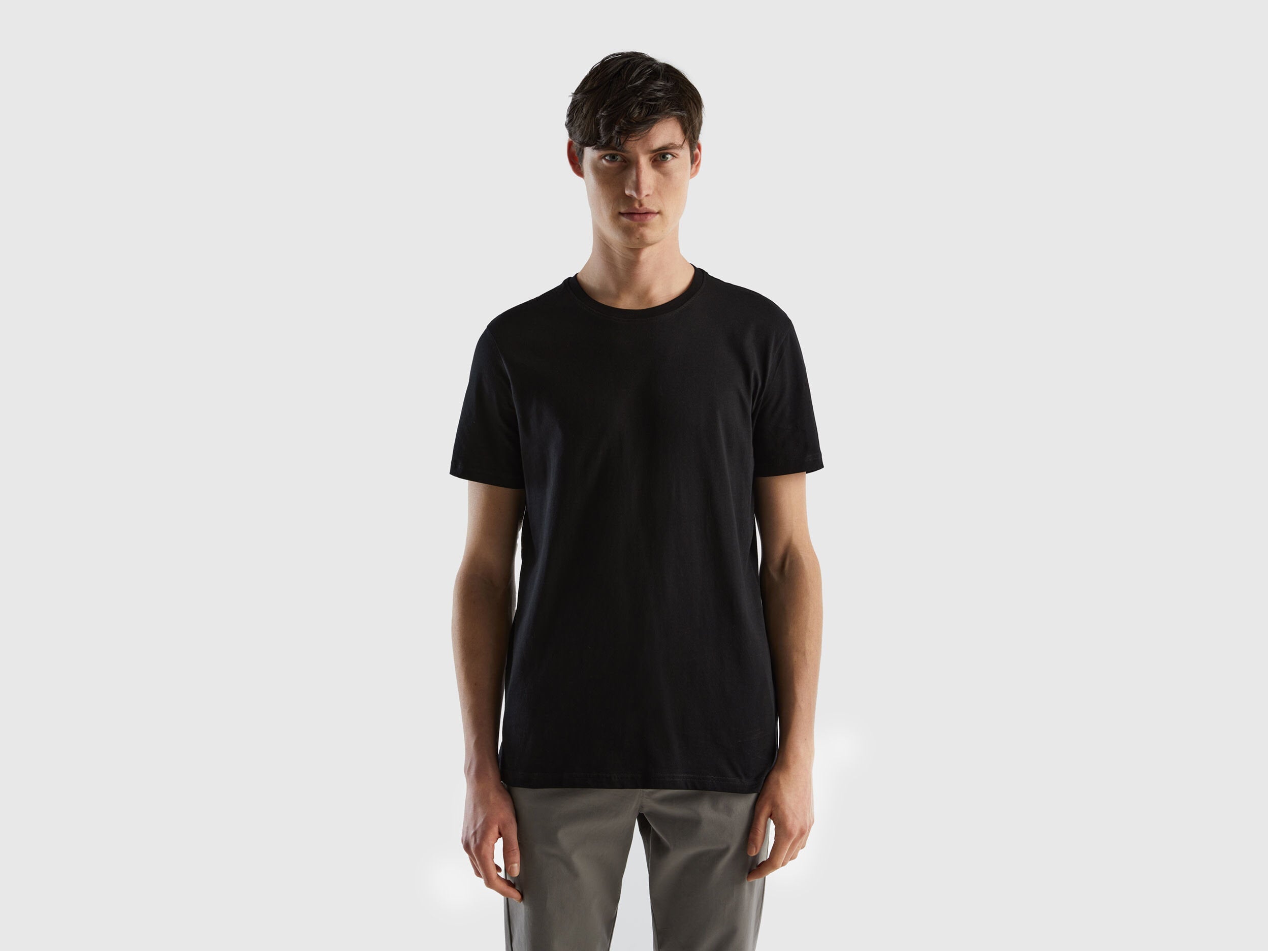 Male model wearing a classic black t-shirt, presented from the front, paired with casual pants.