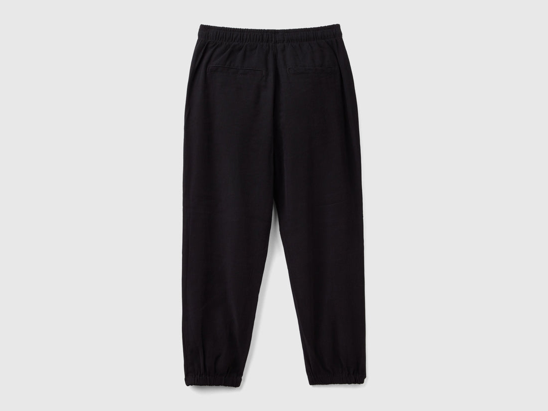 Back view of black parachute trousers with an elasticated waist and cuffs, offering a relaxed fit for casual and comfortable wear in Kuwait.