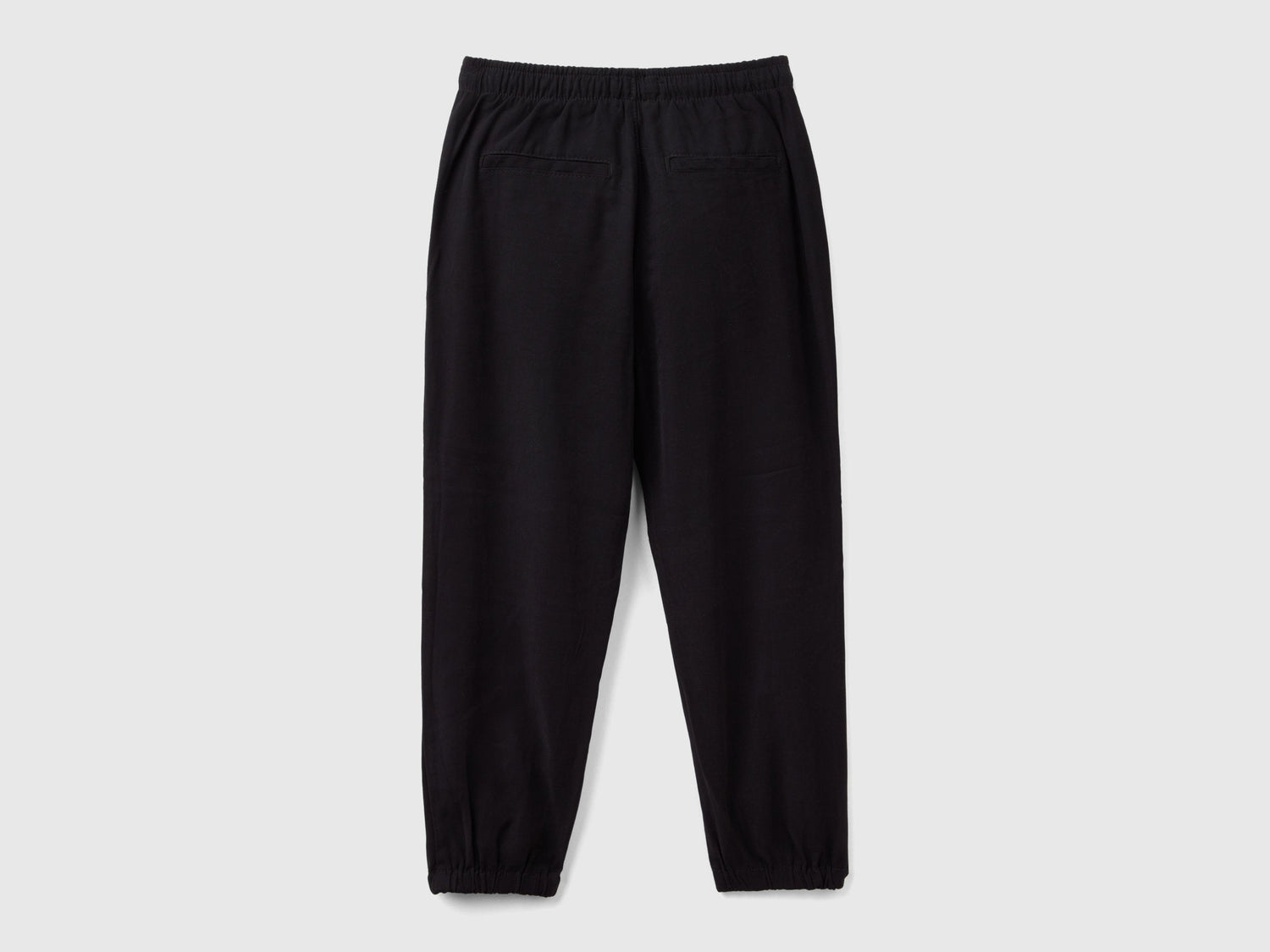 Back view of black parachute trousers with an elasticated waist and cuffs, offering a relaxed fit for casual and comfortable wear in Kuwait.