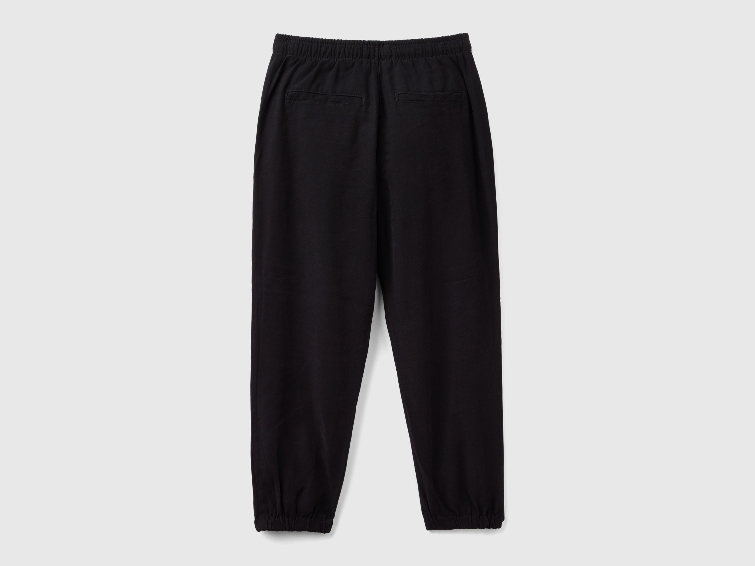 Back view of black parachute trousers with an elasticated waist and cuffs, offering a relaxed fit for casual and comfortable wear in Kuwait.