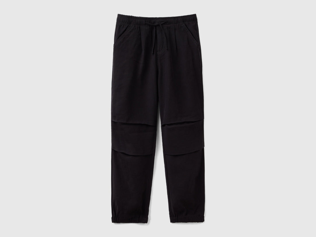 Front view of black parachute trousers with a drawstring waist and knee detailing, a comfortable and stylish choice for active wear in Kuwait.