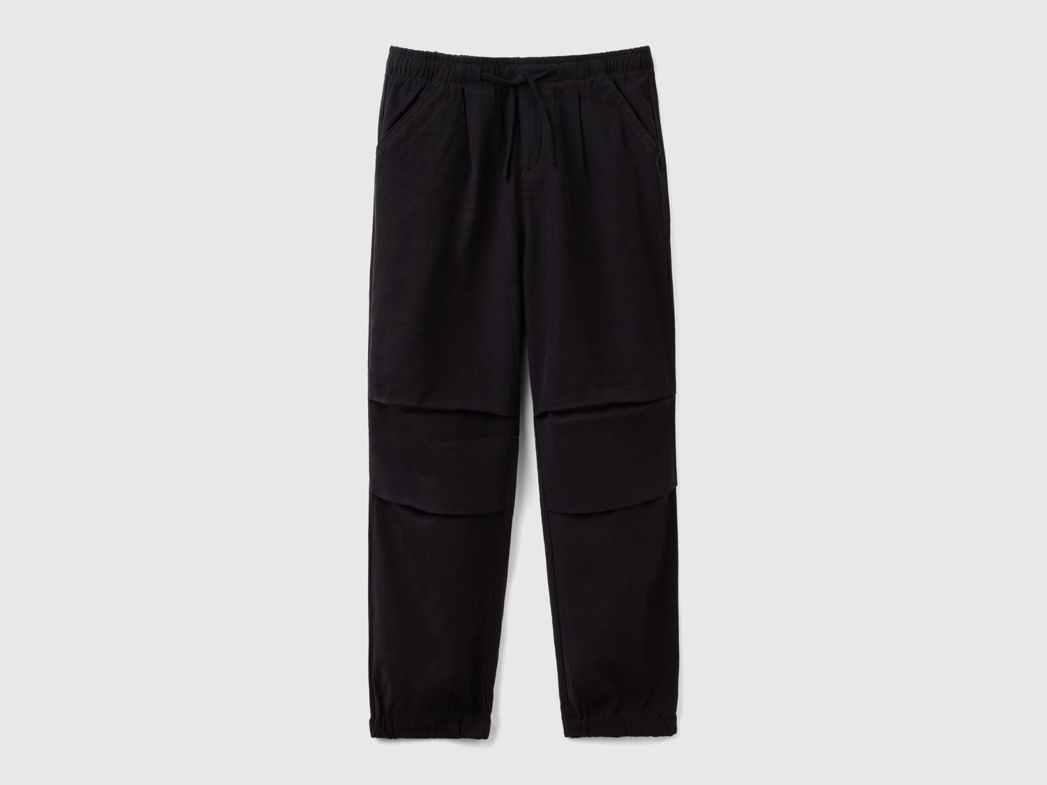 Front view of black parachute trousers with a drawstring waist and knee detailing, a comfortable and stylish choice for active wear in Kuwait.