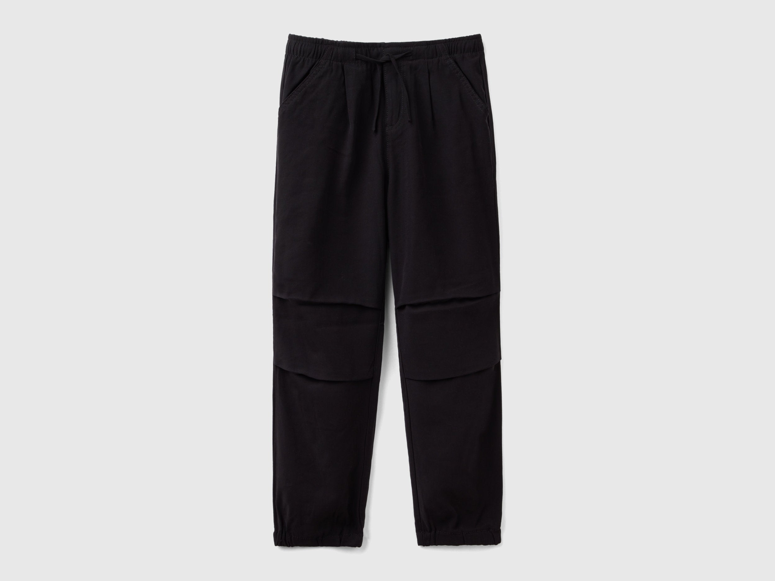 Front view of black parachute trousers with a drawstring waist and knee detailing, a comfortable and stylish choice for active wear in Kuwait.
