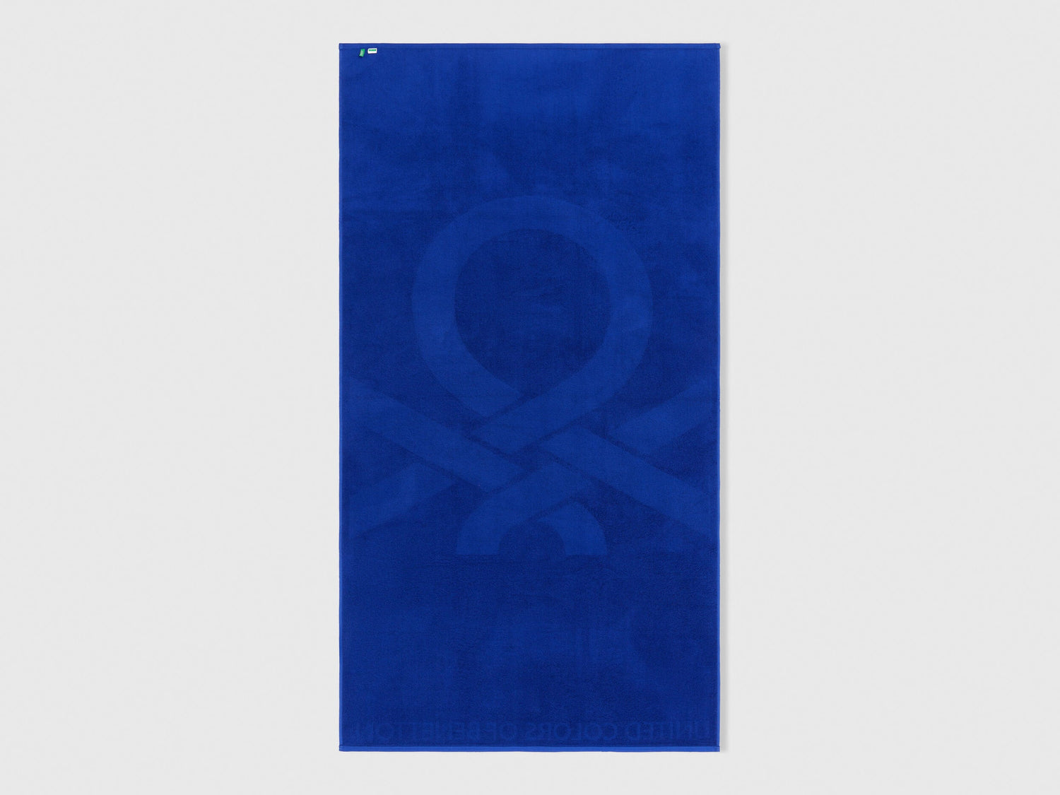 Folded blue Benetton beach towel, showcasing its soft texture and compact size. Travel-friendly.