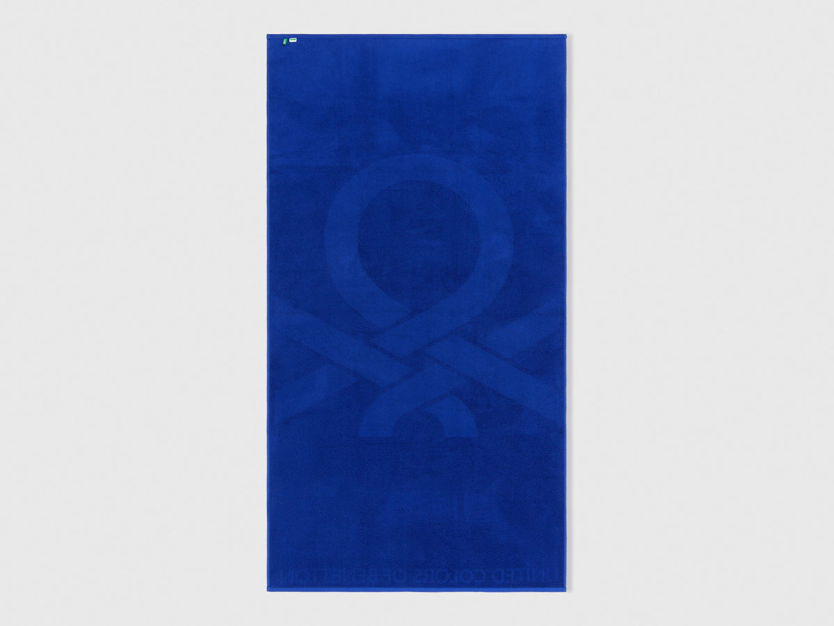 Folded blue Benetton beach towel, showcasing its soft texture and compact size. Travel-friendly.