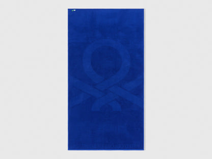 Folded blue Benetton beach towel, showcasing its soft texture and compact size. Travel-friendly.