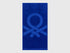 Full view of a vibrant blue Benetton beach towel with large brand logo. Soft and absorbent.