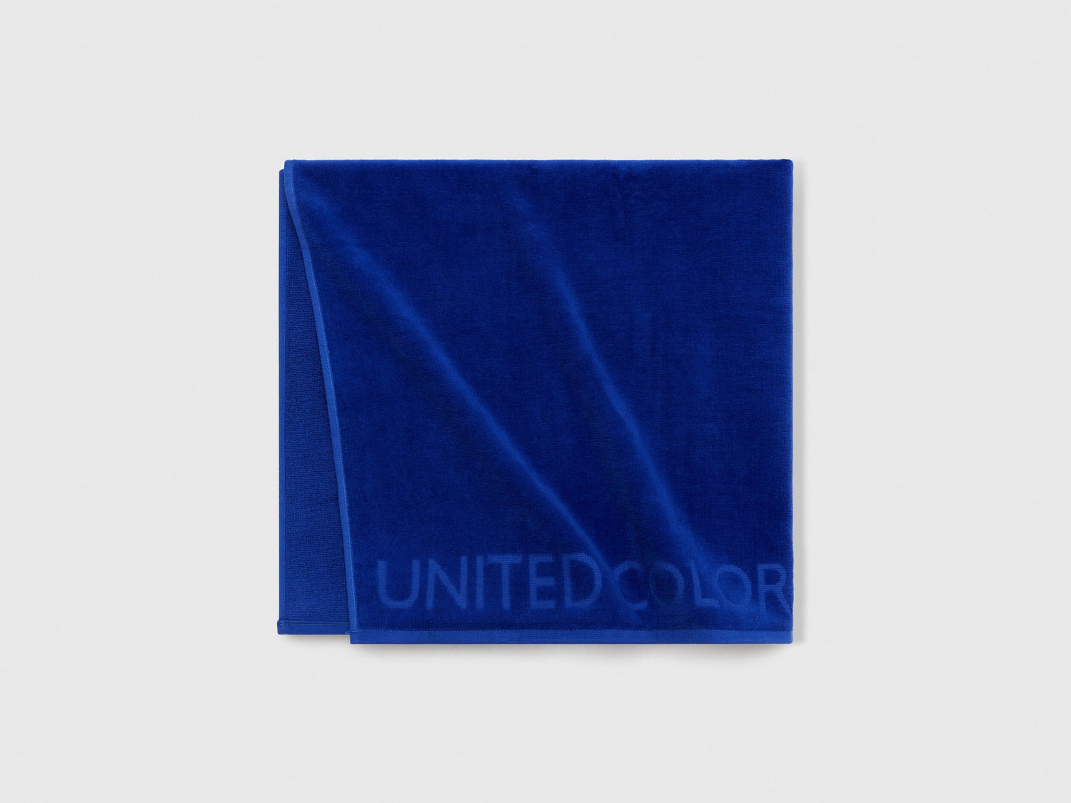 Close-up of blue Benetton beach towel, highlighting its woven texture and subtle pattern.
