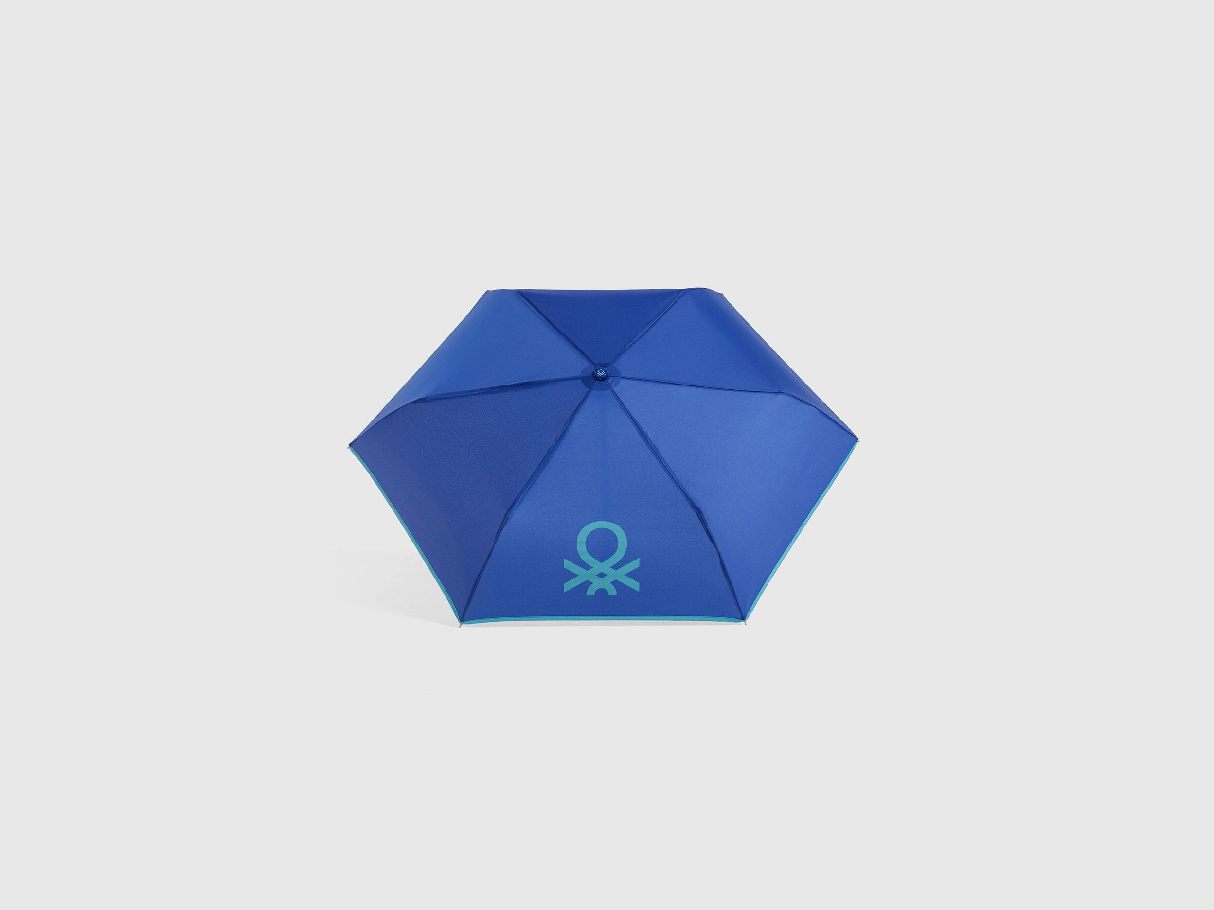 Open blue Benetton umbrella, top view for rain protection.