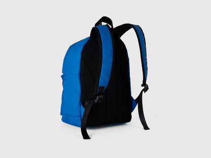 Side view of a blue and black nylon backpack, showcasing the padded shoulder straps and back panel.