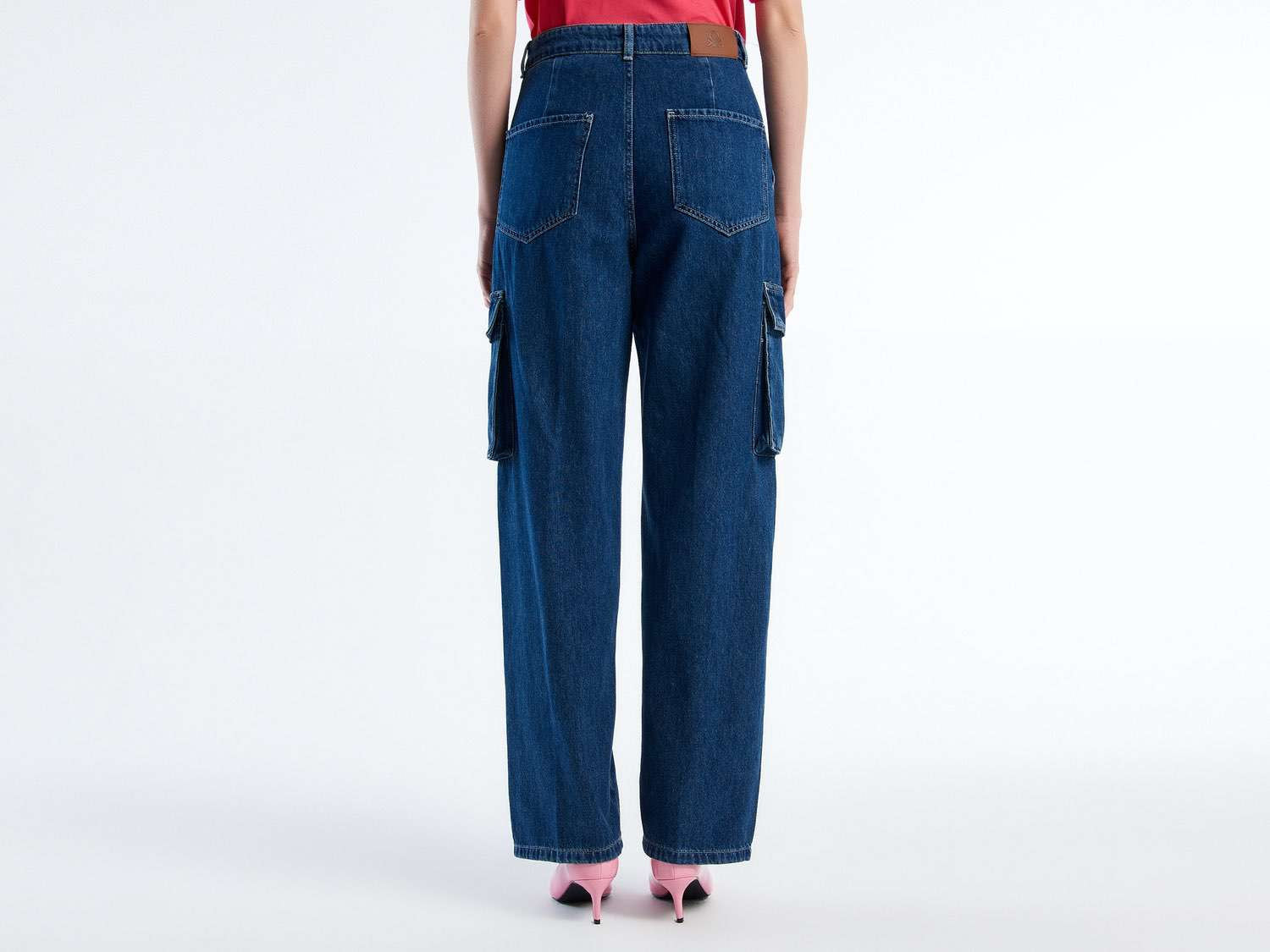 Back view of a woman wearing dark blue cargo trousers and pink heels. Wide leg, relaxed fit.