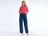 Front view of a woman wearing dark blue cargo trousers with a pink top and heels. Casual style.