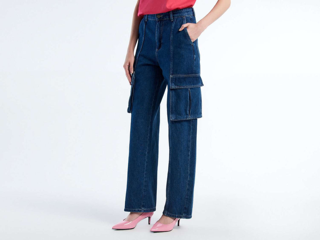 Side view of a woman wearing dark blue cargo trousers and pink heels. Features large side pockets.