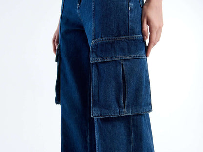 Close-up of the large side cargo pocket on dark blue trousers, showing denim texture.