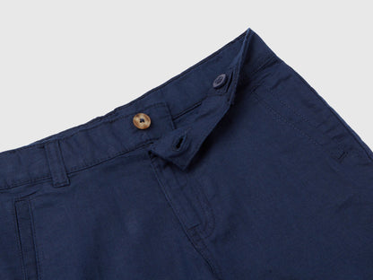 A close-up view of the fly and waist details of dark blue linen blend shorts, showing the button closure and belt loops.